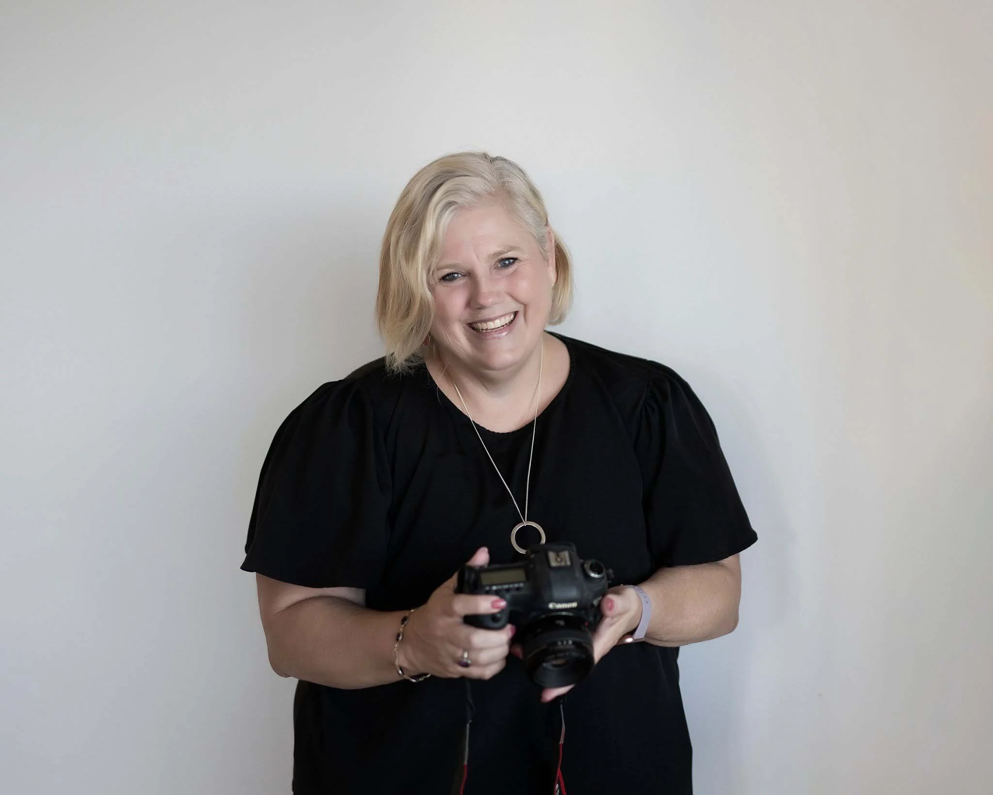 Kate, owner and photographer, holding her camera at her Gordon headshot studio