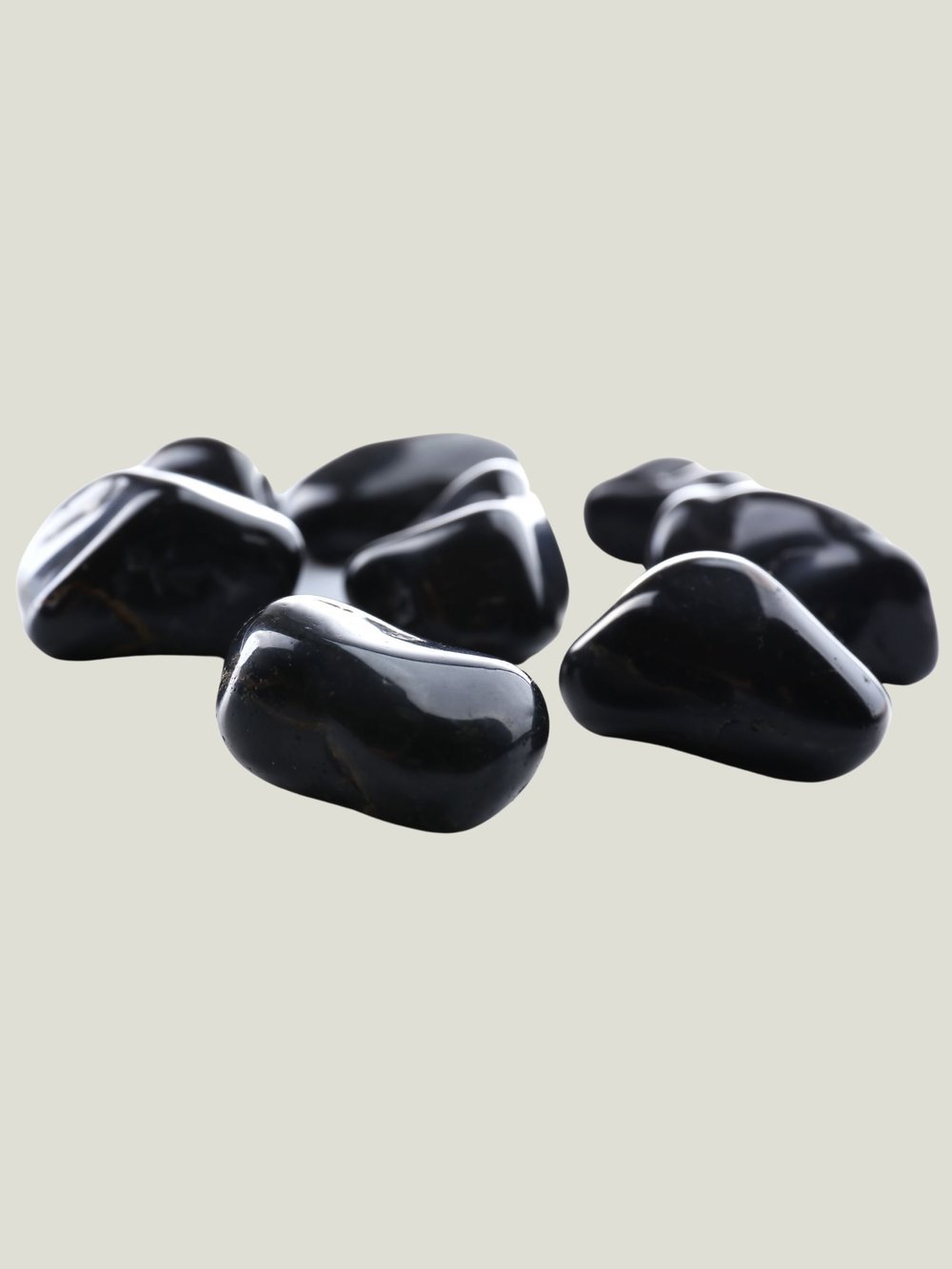 Group of black polished stones on a light background.