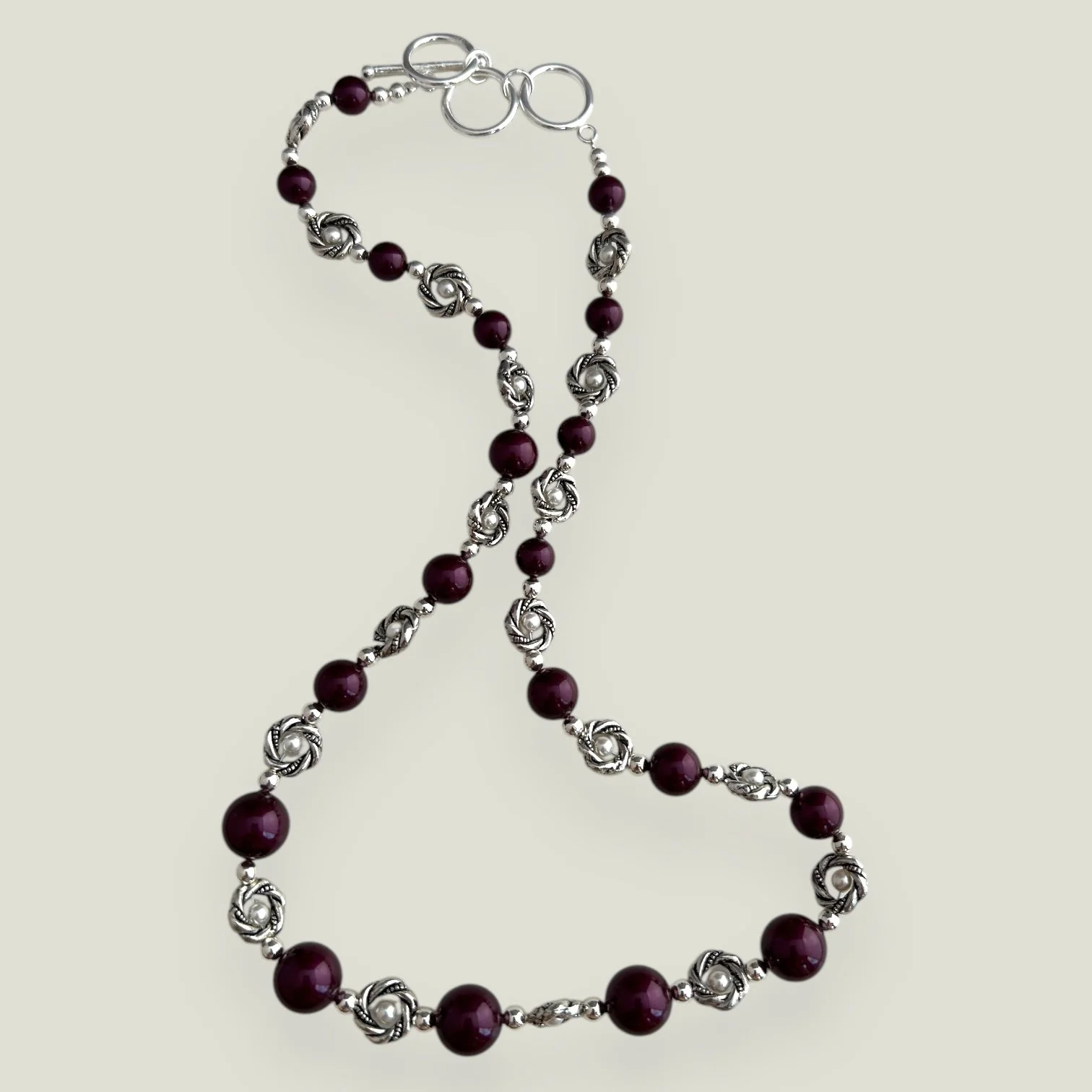 Custom silver necklace made for a client with Blackberry Swarovski pearls and silver twisted knot details.