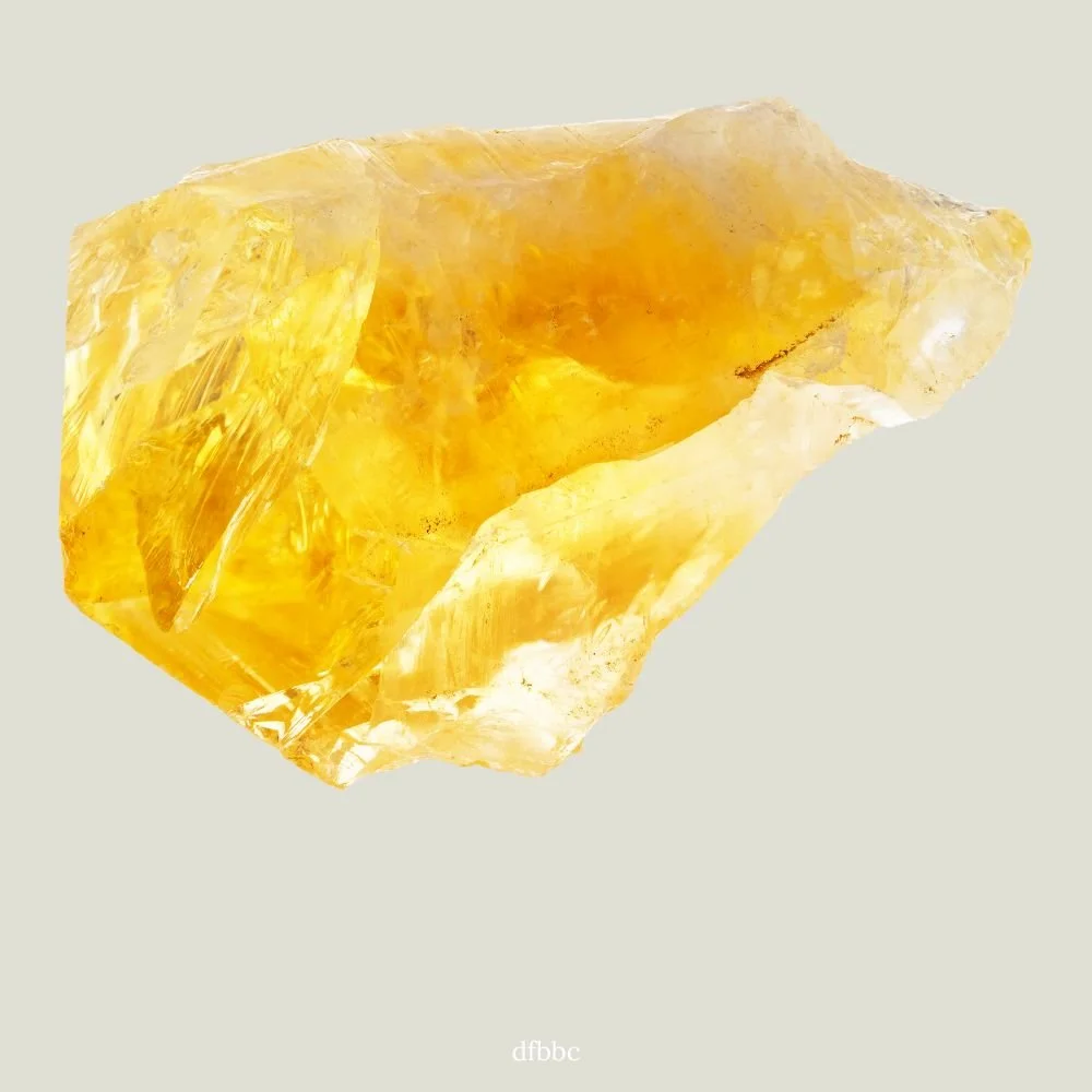 A large, rough, yellow gemstone or mineral specimen against a plain, light background.