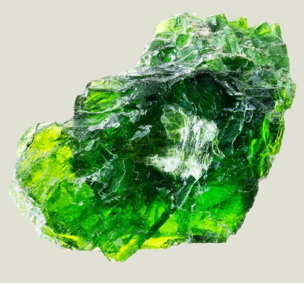 Close-up of a rough, irregularly shaped green glass or mineral specimen with transparent and reflective qualities.