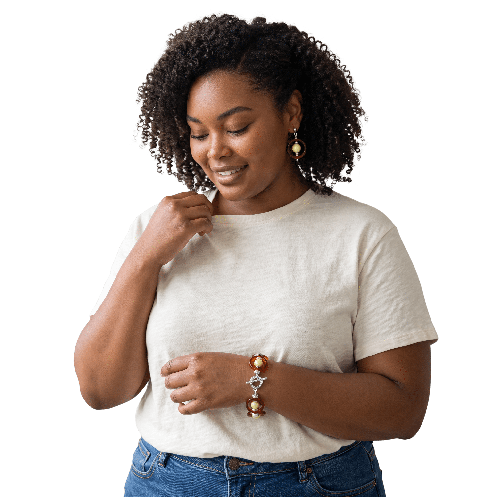 Close-up of a woman with curly dark hair wearing a white shirt and denim jeans, smiling with her eyes closed, looking down, with her left hand near her chin.