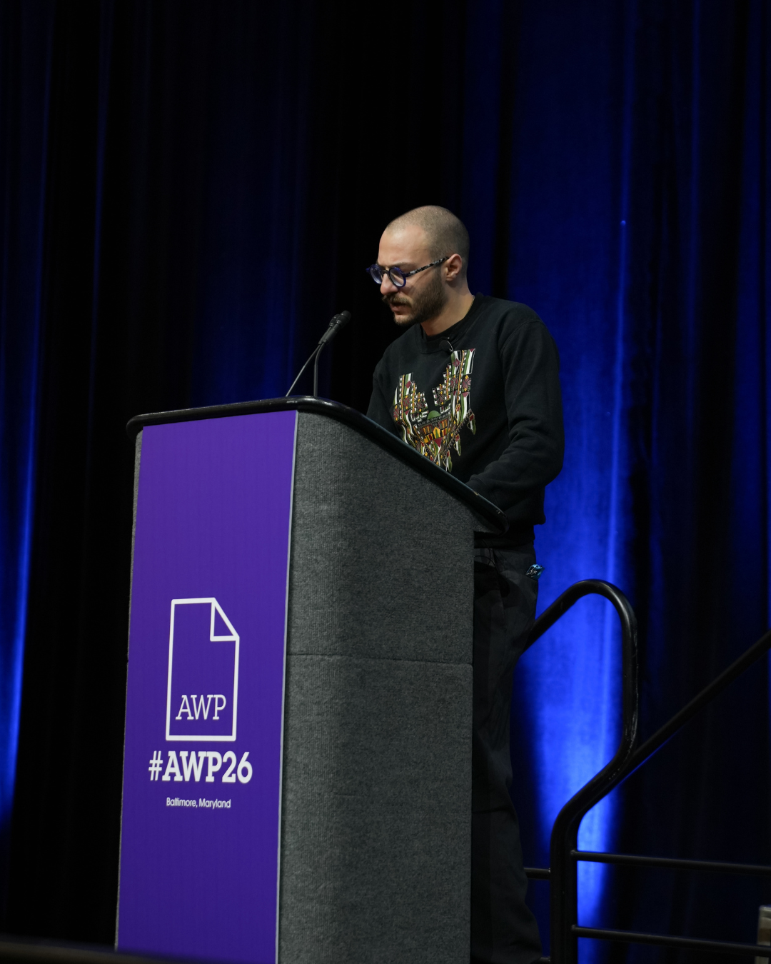 Fargo Nissim Tbakhi reading at the podium.