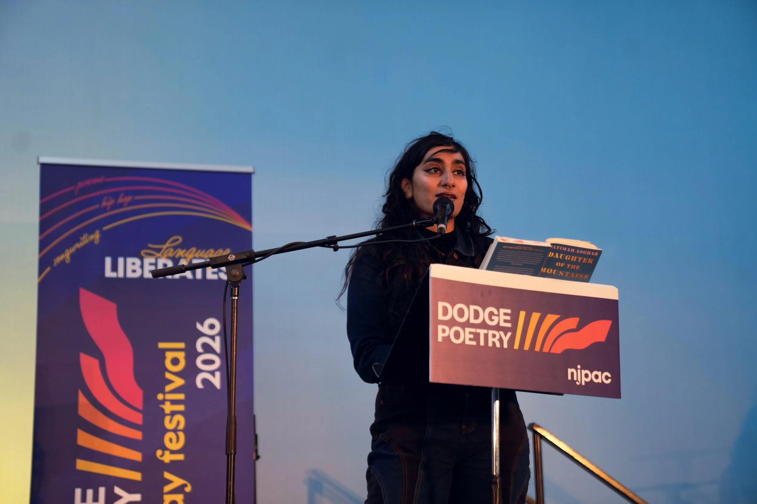 A writer reads from behind a podium with their book in their hands.