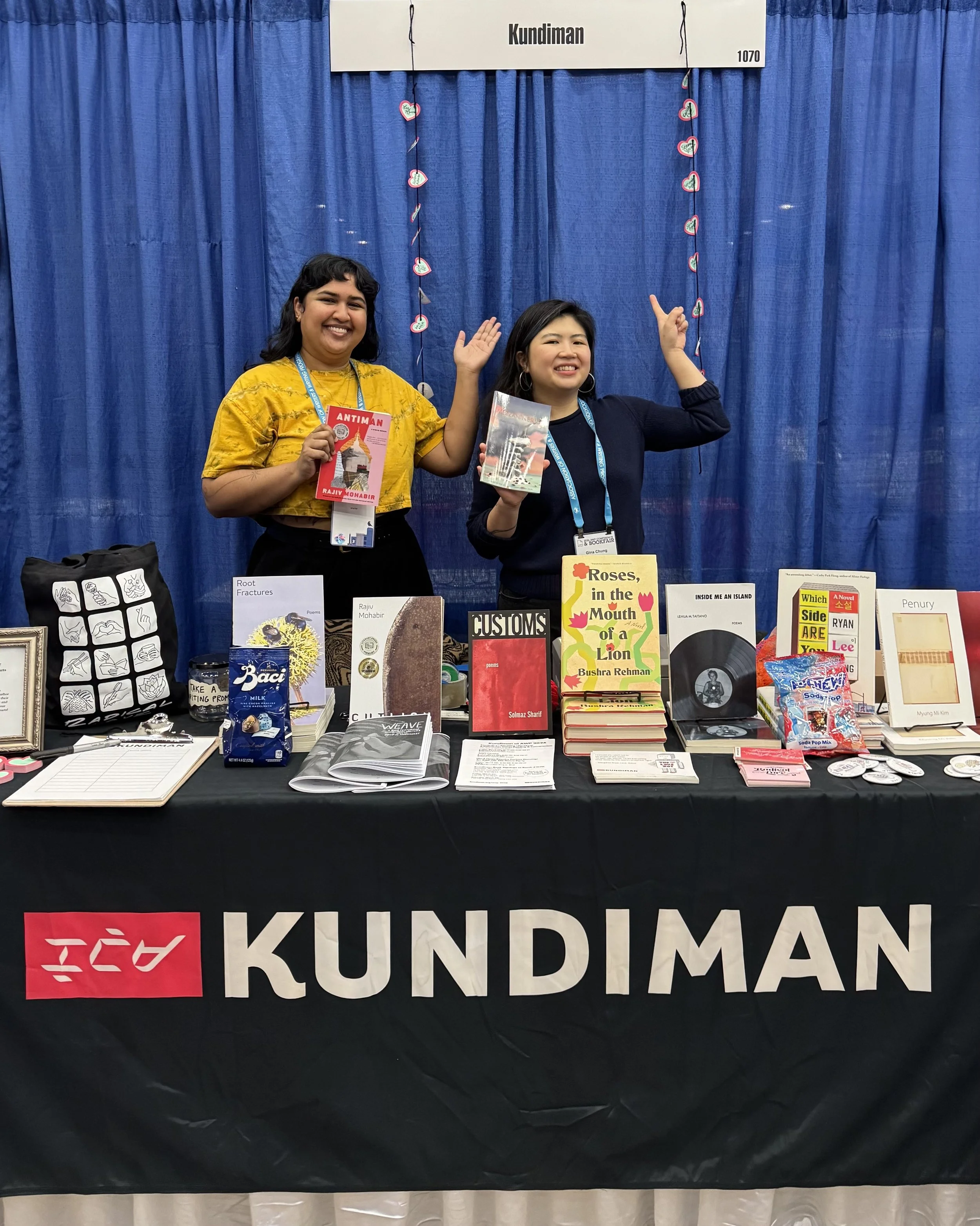 Niv Sekar and Gina Chung holding up books at the Kundiman booth during AWP.