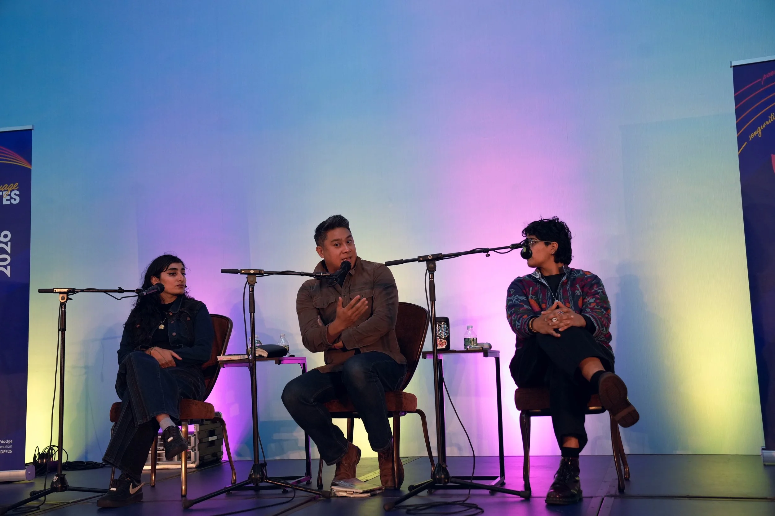 Three writers sit on stage behind microphones.