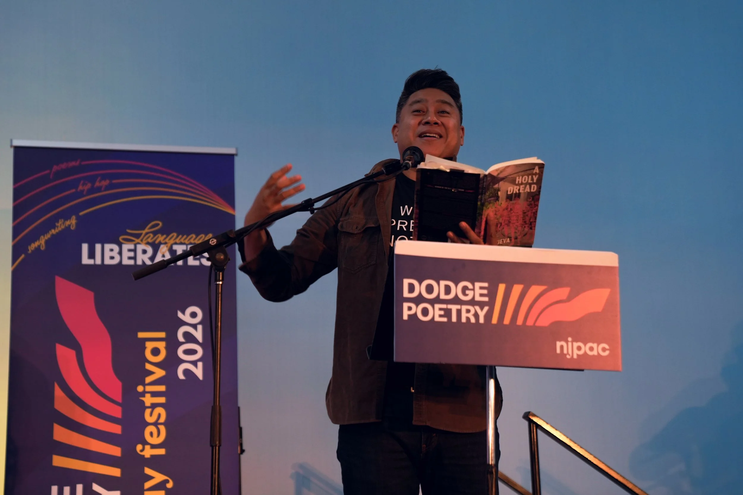 A writer reads from behind a podium with their book in their hands.