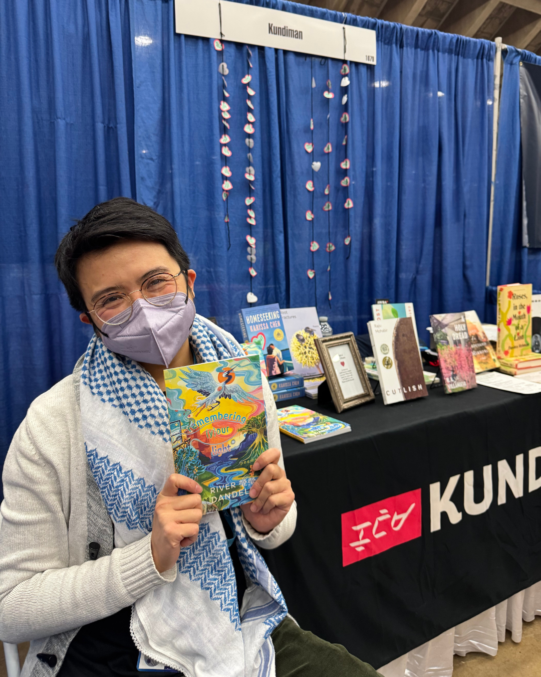 River 瑩瑩 Dandelion holding up their book at the Kundiman booth.