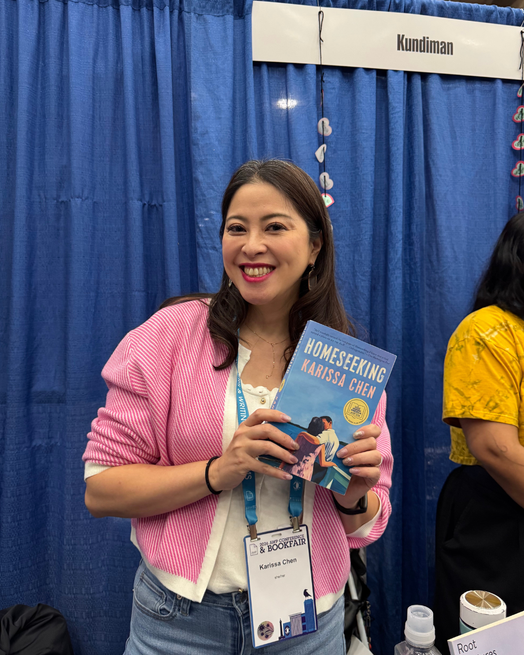 Karissa Chen holding up her book at the Kundiman booth.