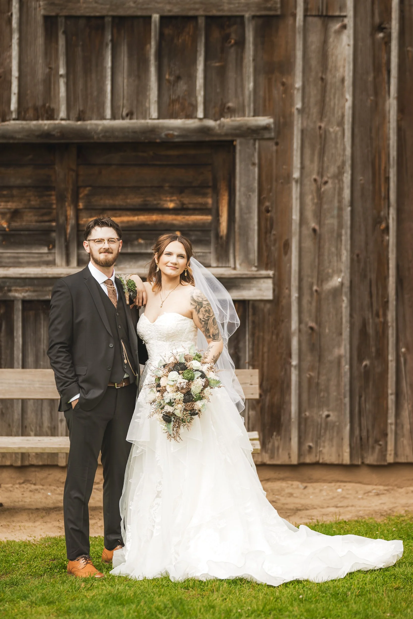 The bride and groom stand in front of the old syrup factory in an editorial style wedding photo at Deep River Park.