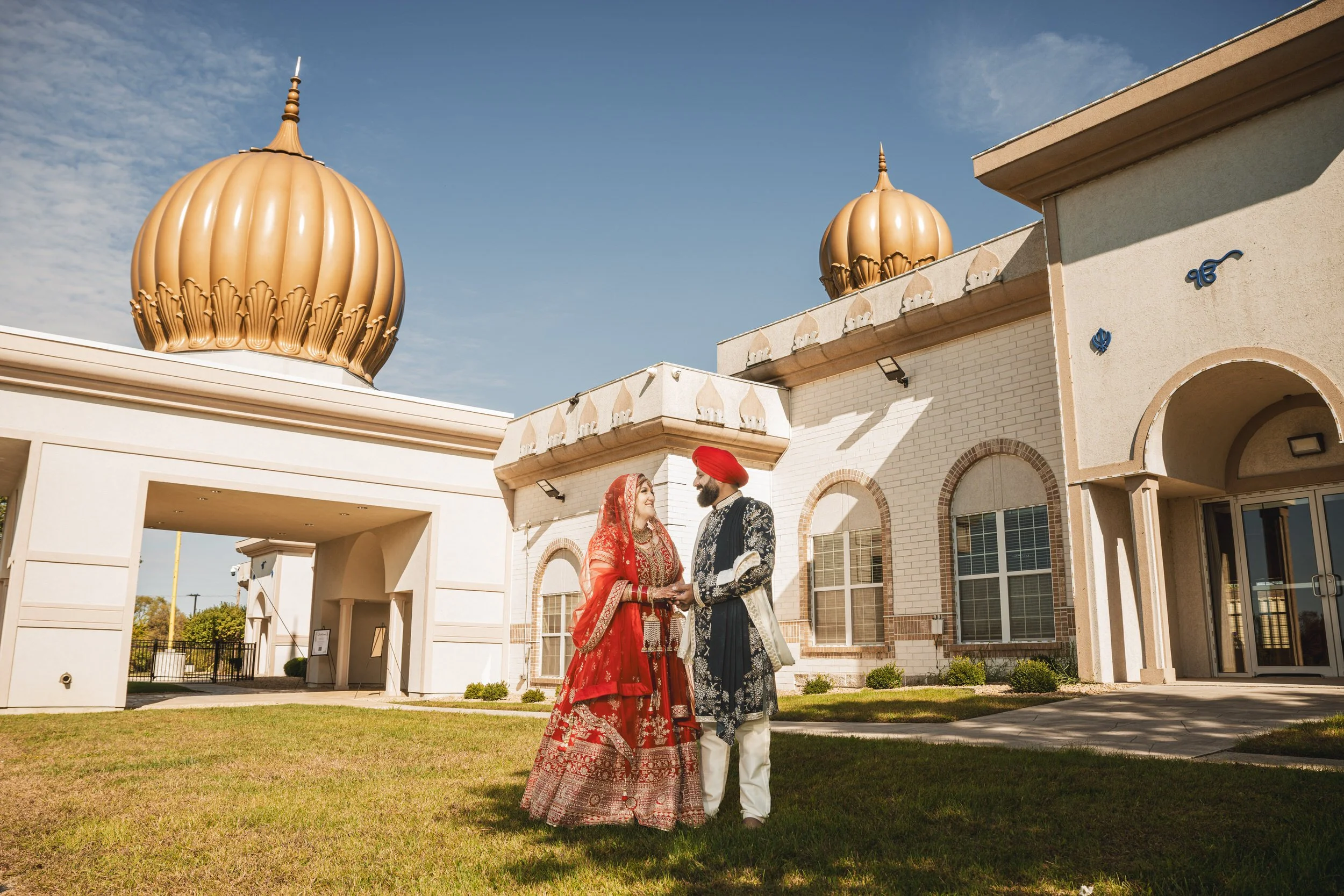 Bride and groom stand underneath the golden domes of Sikh Religious Society of Indiana.