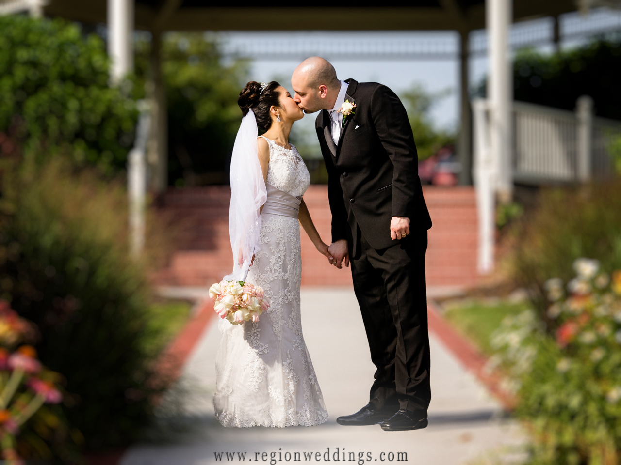 A newly married couple kiss in front of the gazebo at Ellendale Farms in Crown Point, Indiana.