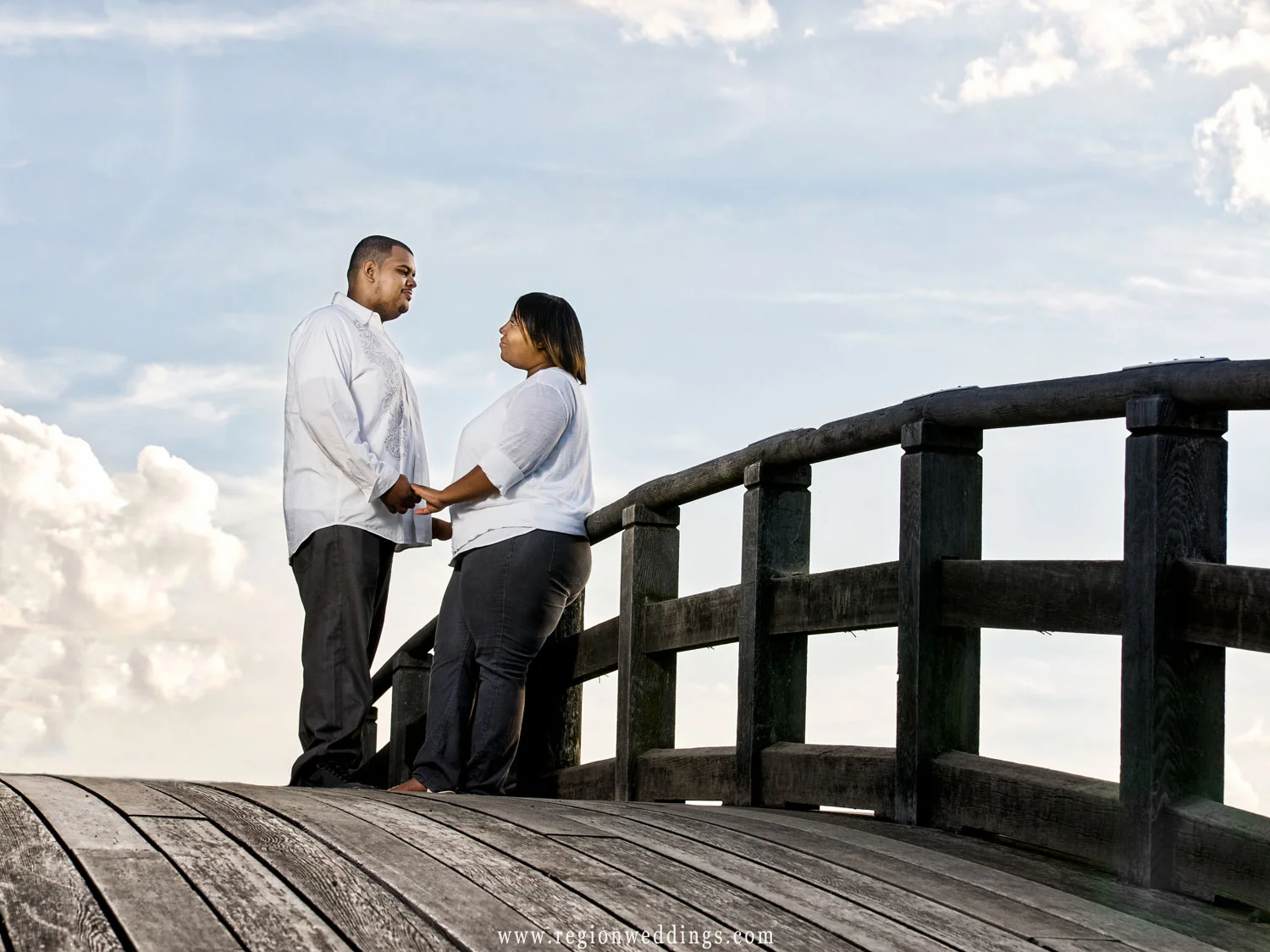 A couple holds hands atop the Marquette Park lagoon bridge.