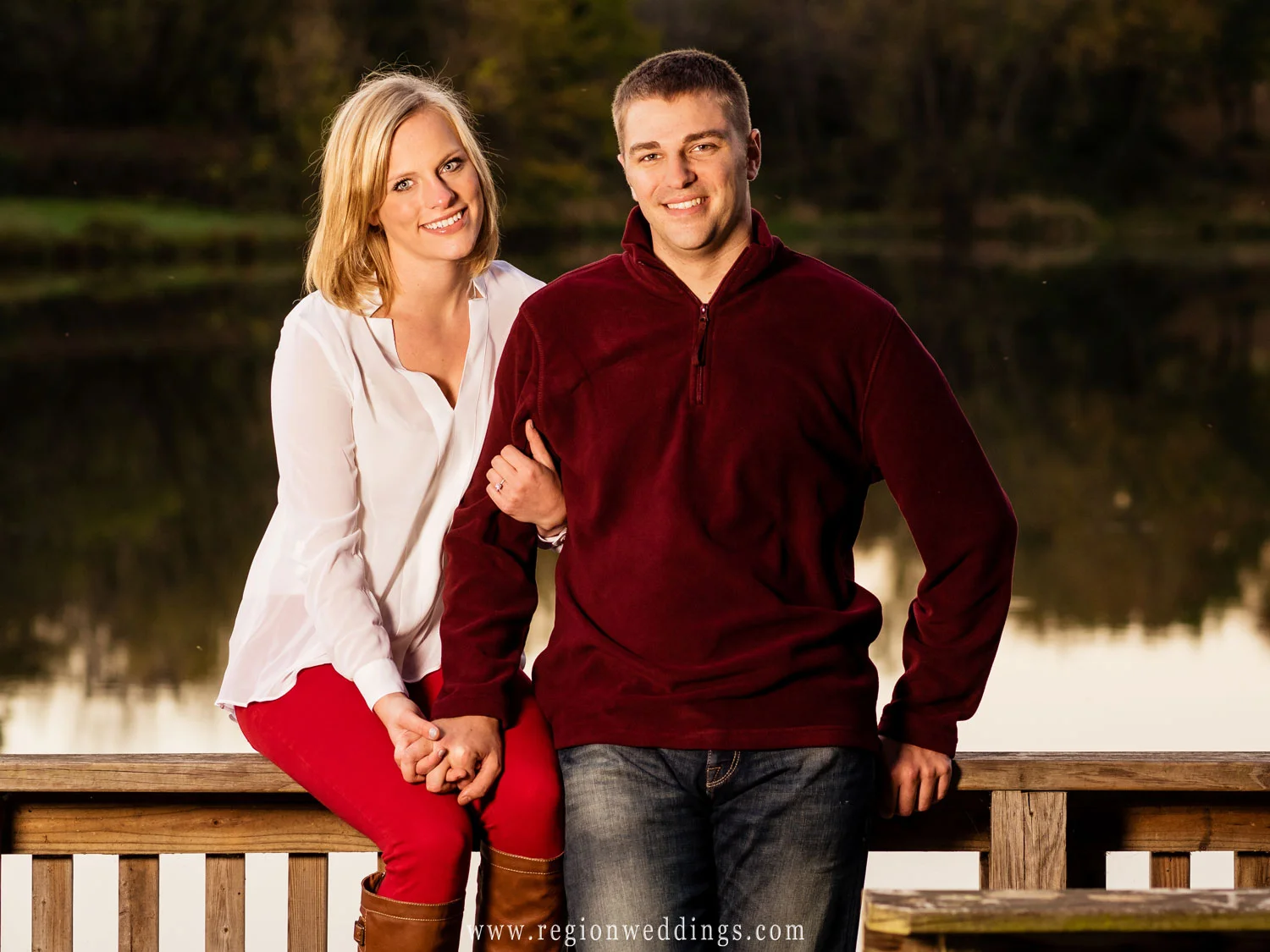 A couple relaxes on the pier overlooking the lake for their engagement photo.