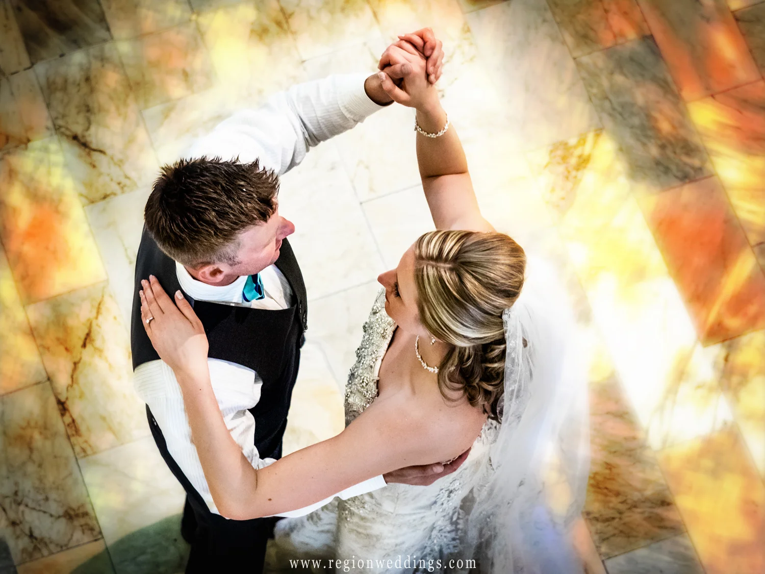 The bride and groom dance upon the marble floor.
