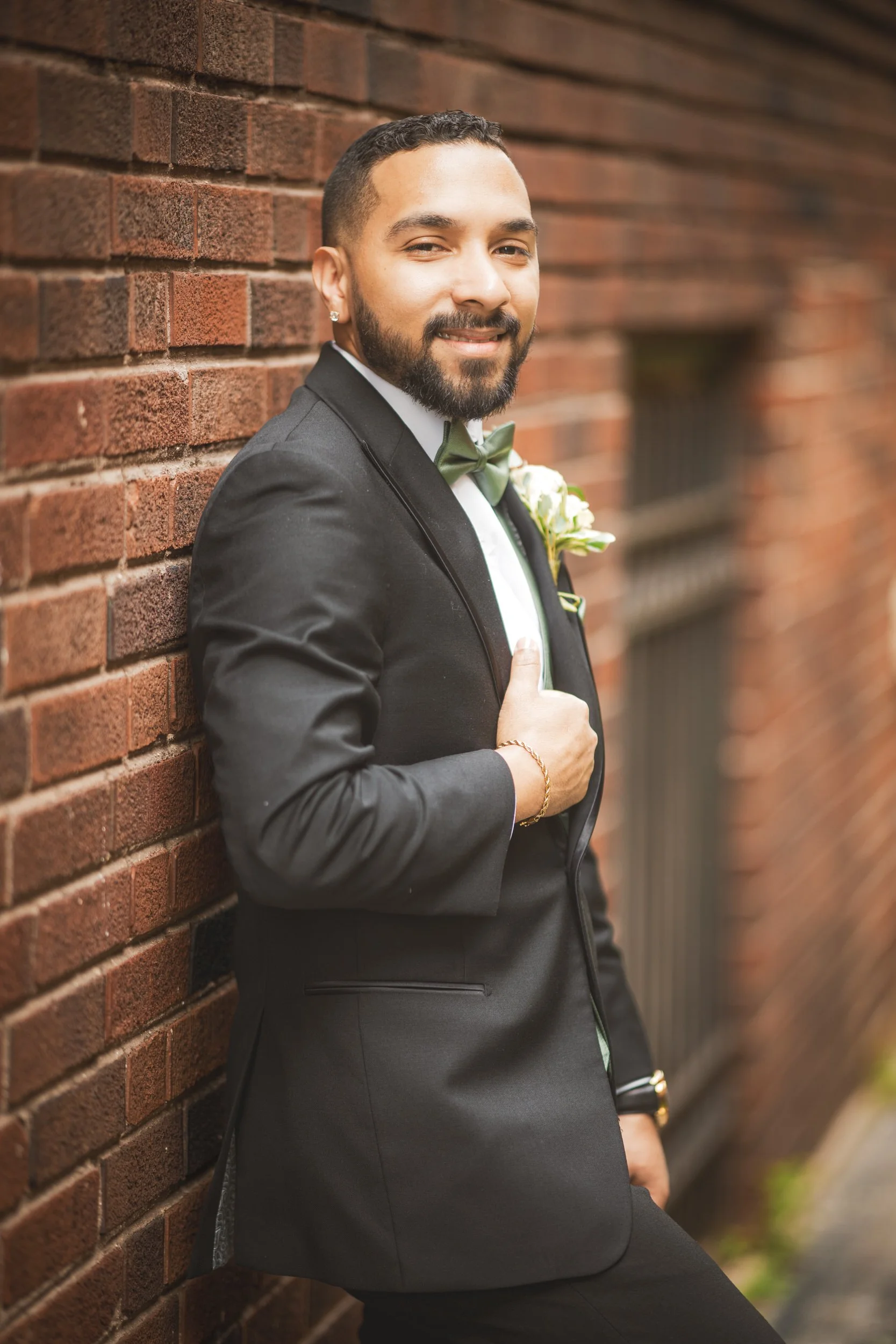 A groom leans against the brick in an alleyway in downtown Crown Point, Indiana.