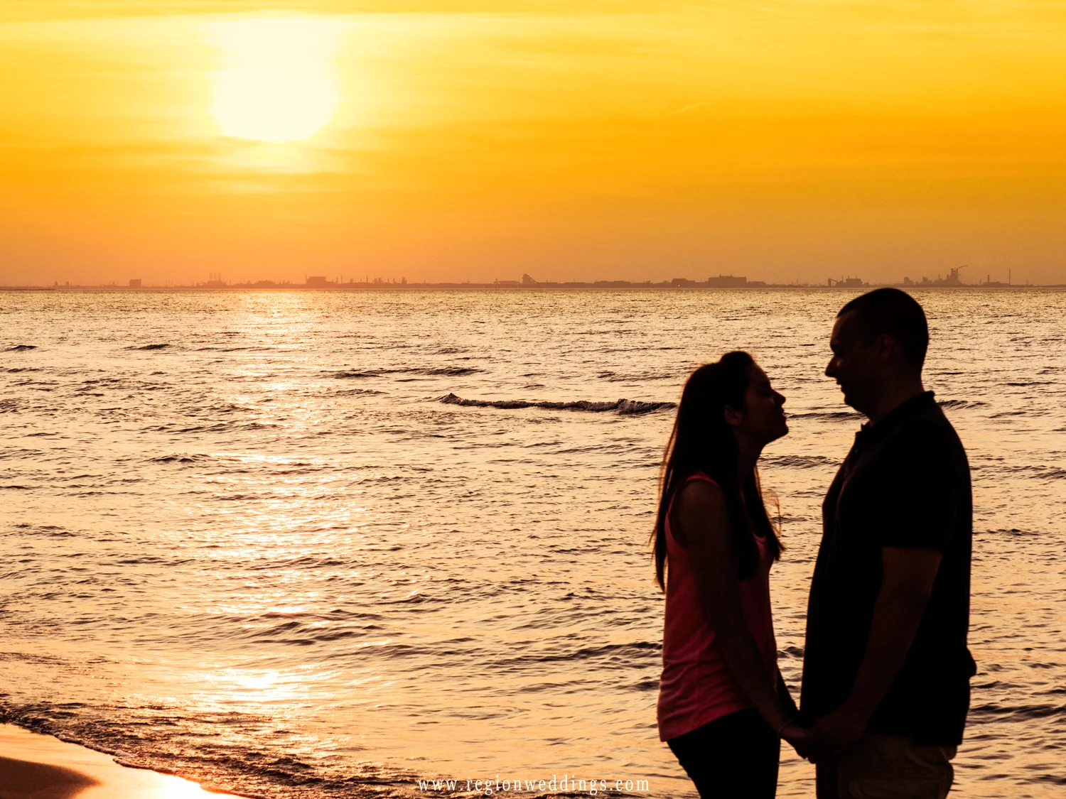 A sunset silouhette of a couple on a Lake Michigan beach.
