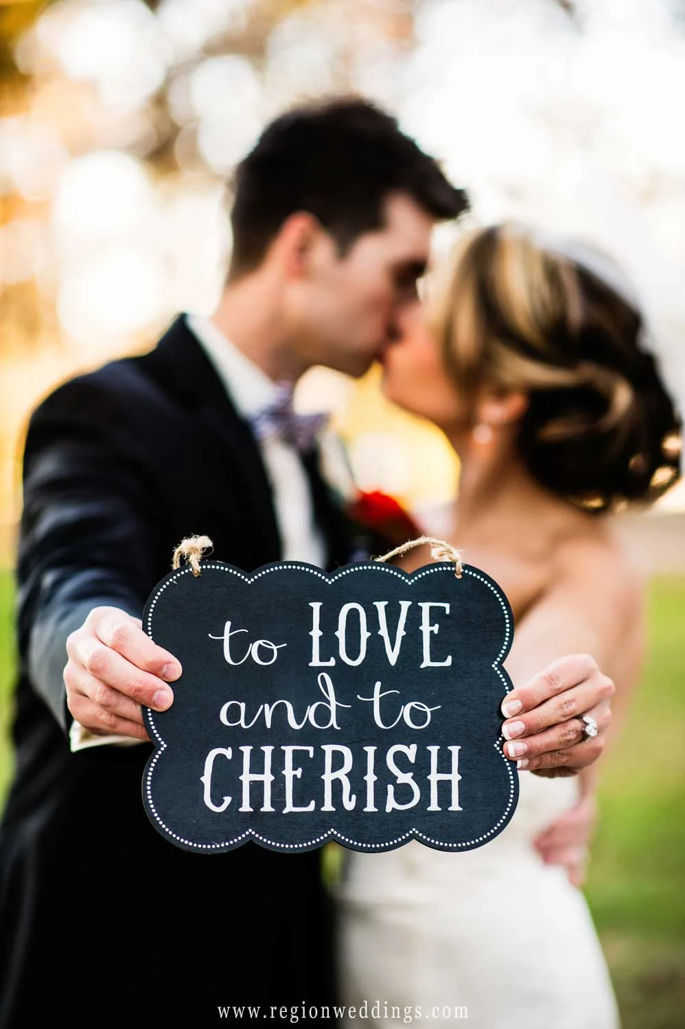 The bride and groom hold a sign that states To Love and To Cherish.