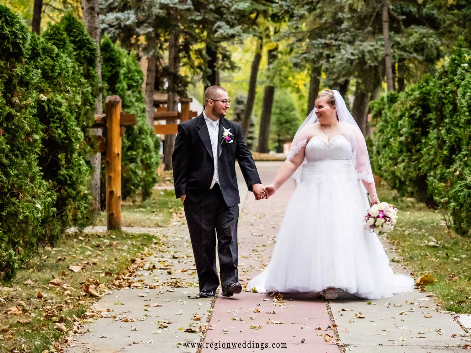 The bride and groom stroll through the walkways of Carmelite Shrine in Munster, Indiana.