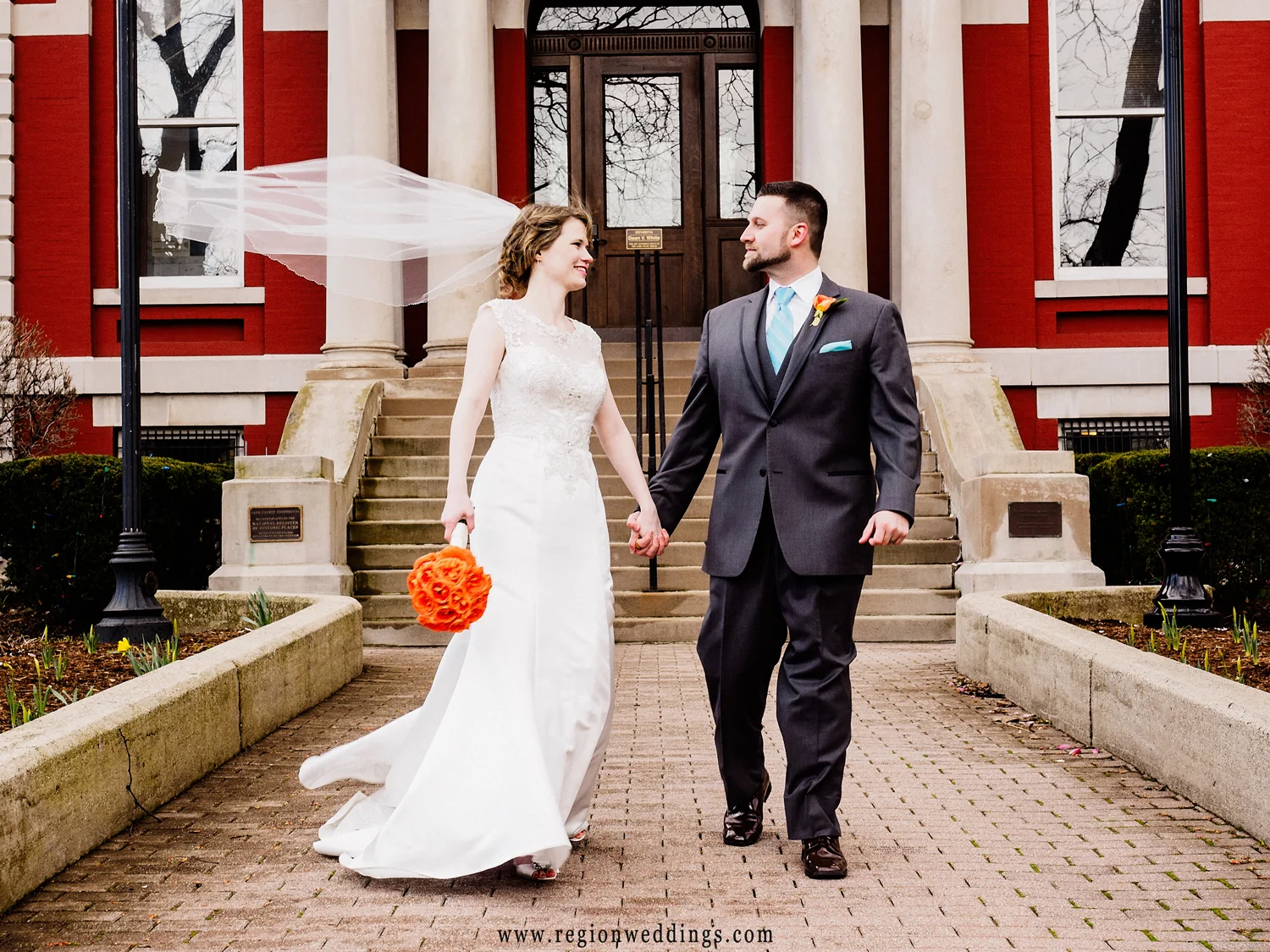 The bride's veil flies in the wind as the newlyweds take a stroll in downtown Crown Point.
