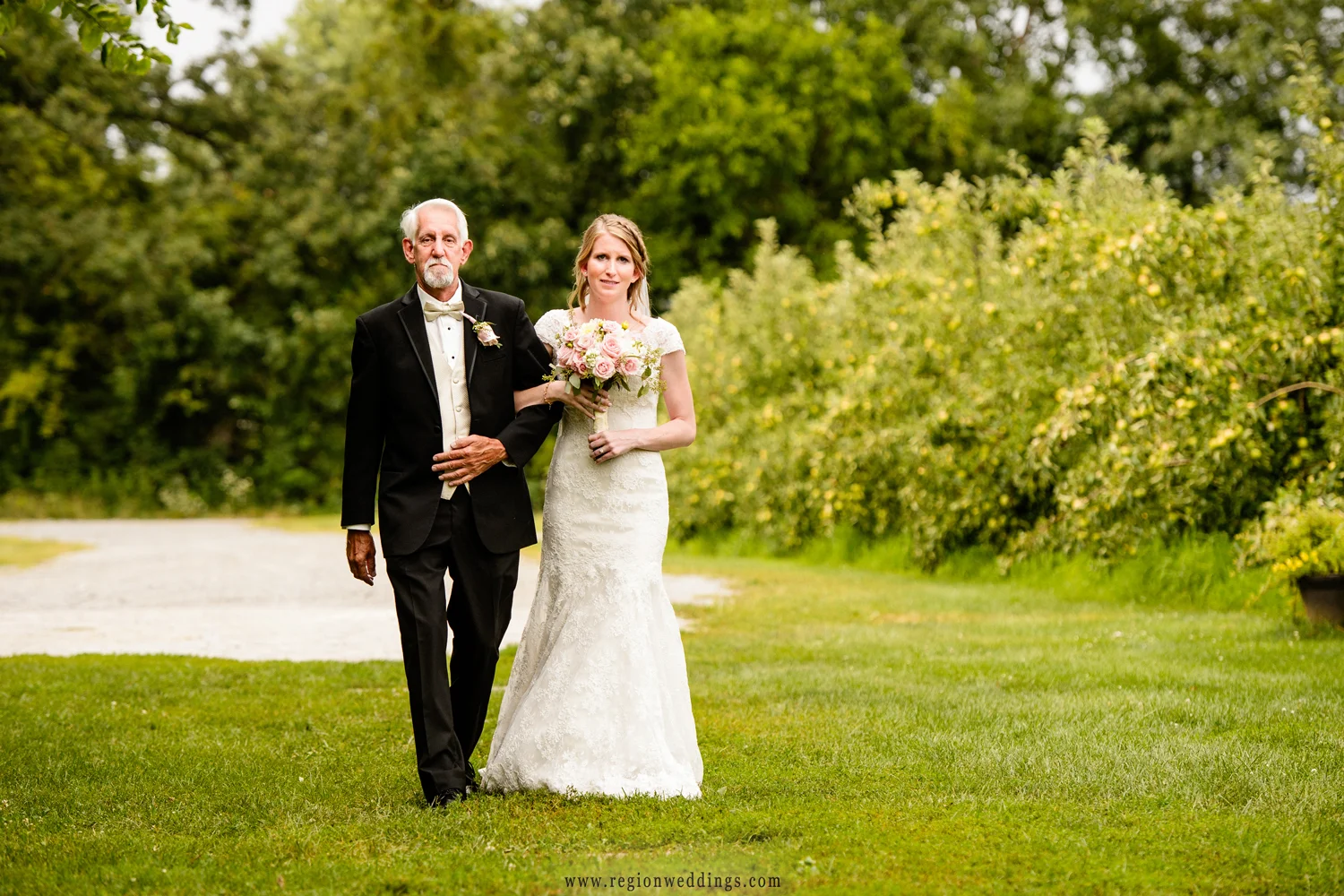 The bride walks down the aisle in an outdoor wedding at County Line Orchard.