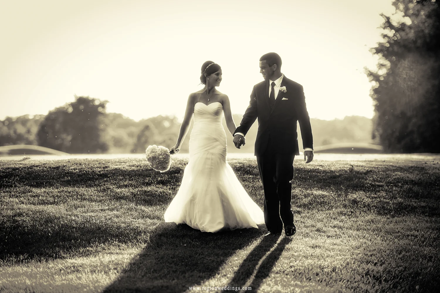 The bride and groom stroll the hills of White Hawk golf course at golden hour.