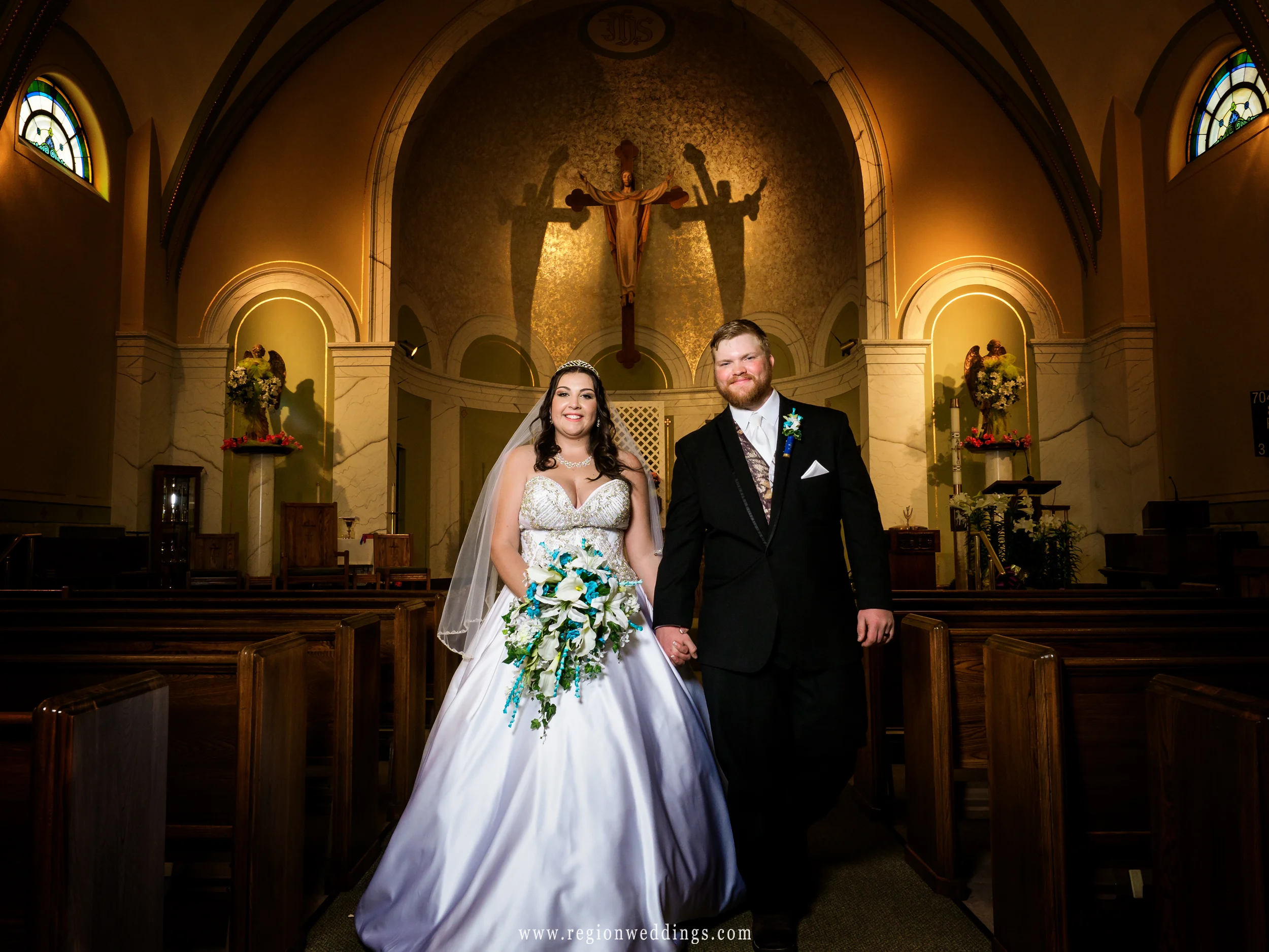 Bride and groom walk in the center aisle of church.