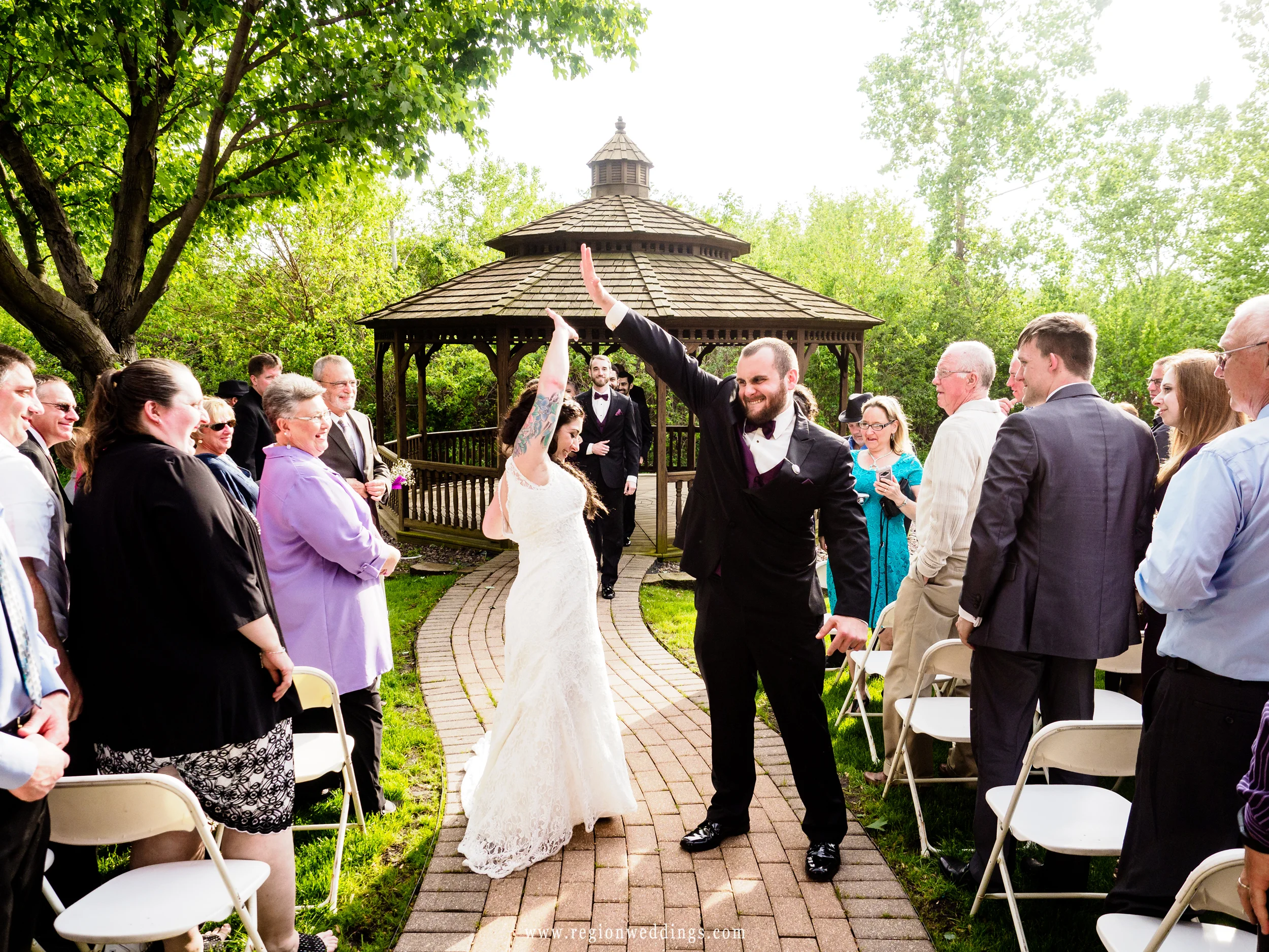 The bride and groom go for a high five as they exit the gazebo at Villa Cesare.