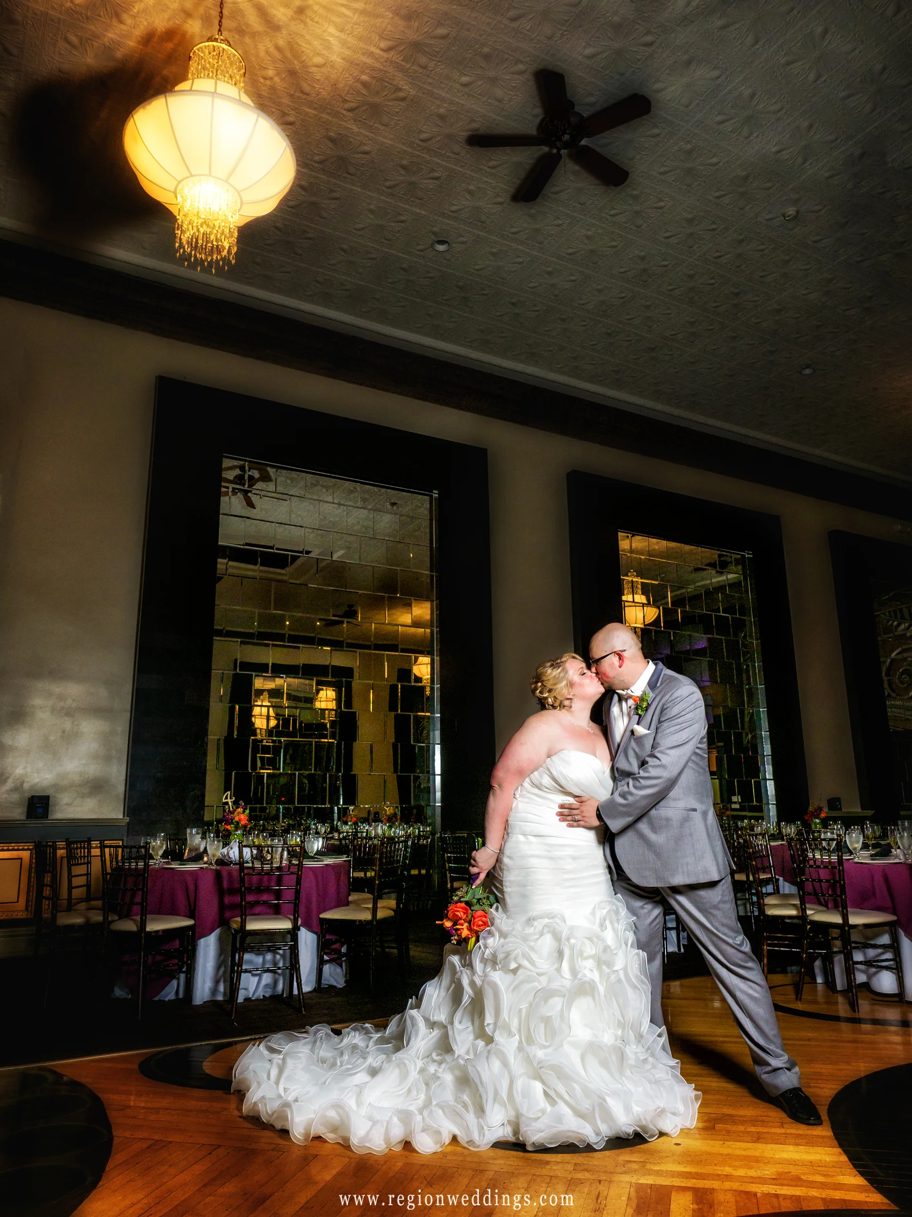 Bride and groom share a kiss in the middle of the ballroom of The Allure.