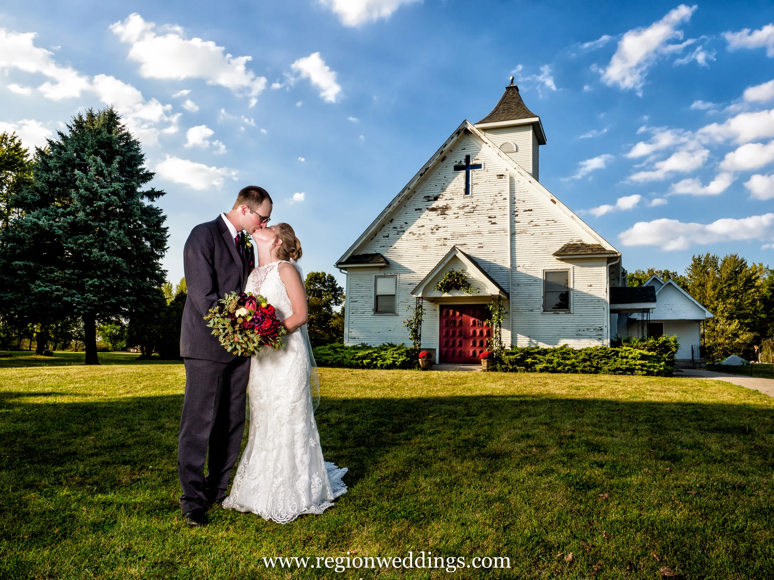 Bride and groom kiss in front an old chapel in Hebron, Indiana.