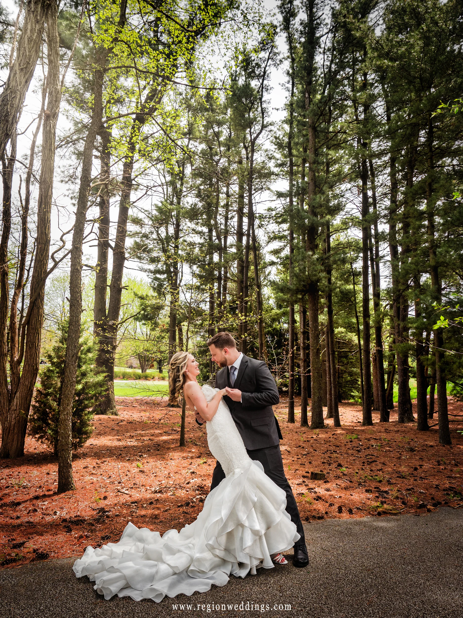 The groom dips his bride underneath some mile high trees.