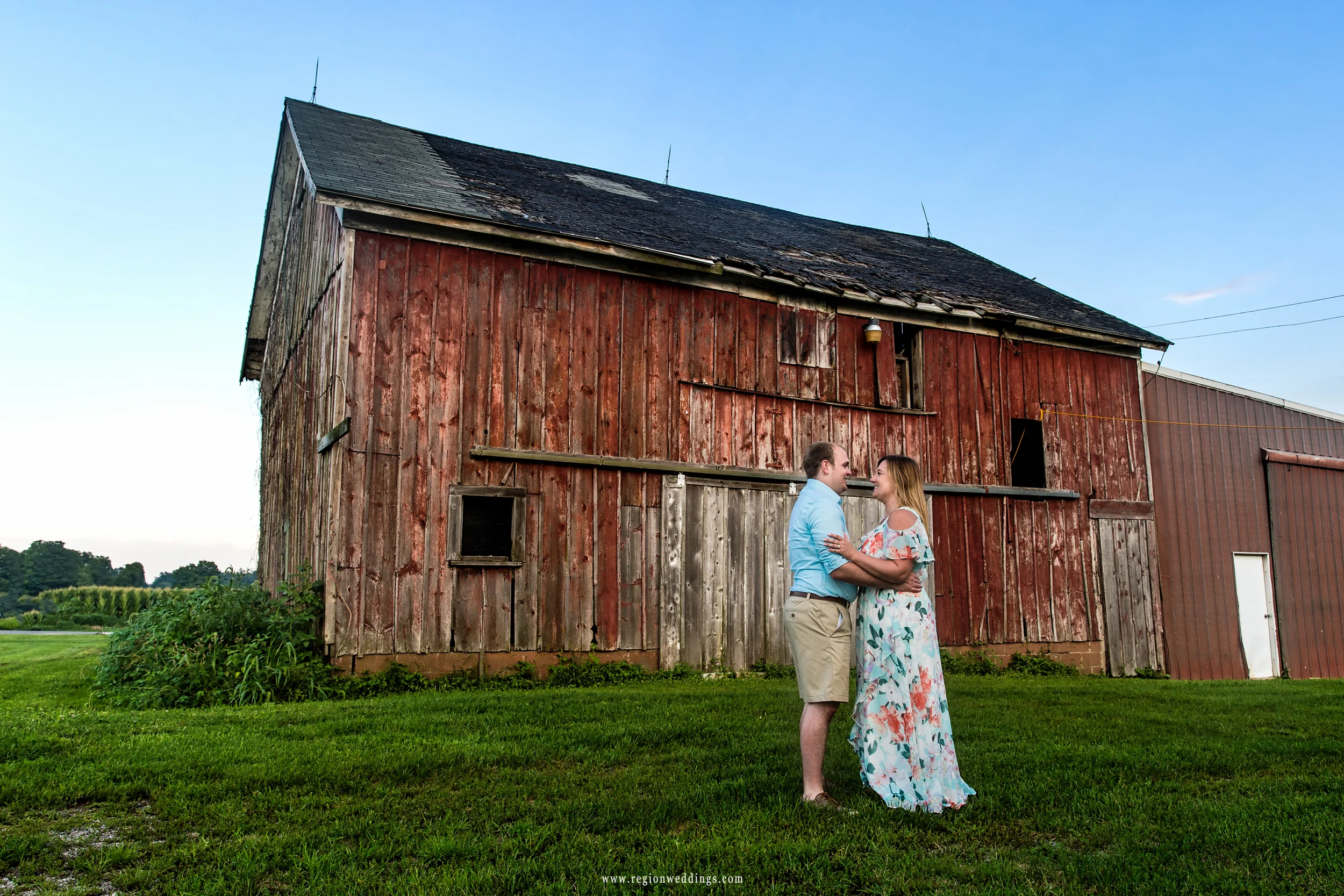 A young couple embraces in front of the Four Corners barn.