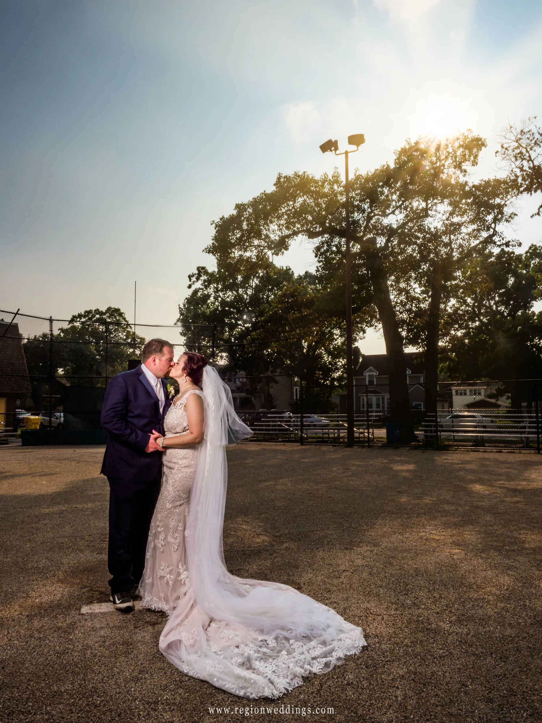 Bride and groom share a kiss on the pitcher's mound.