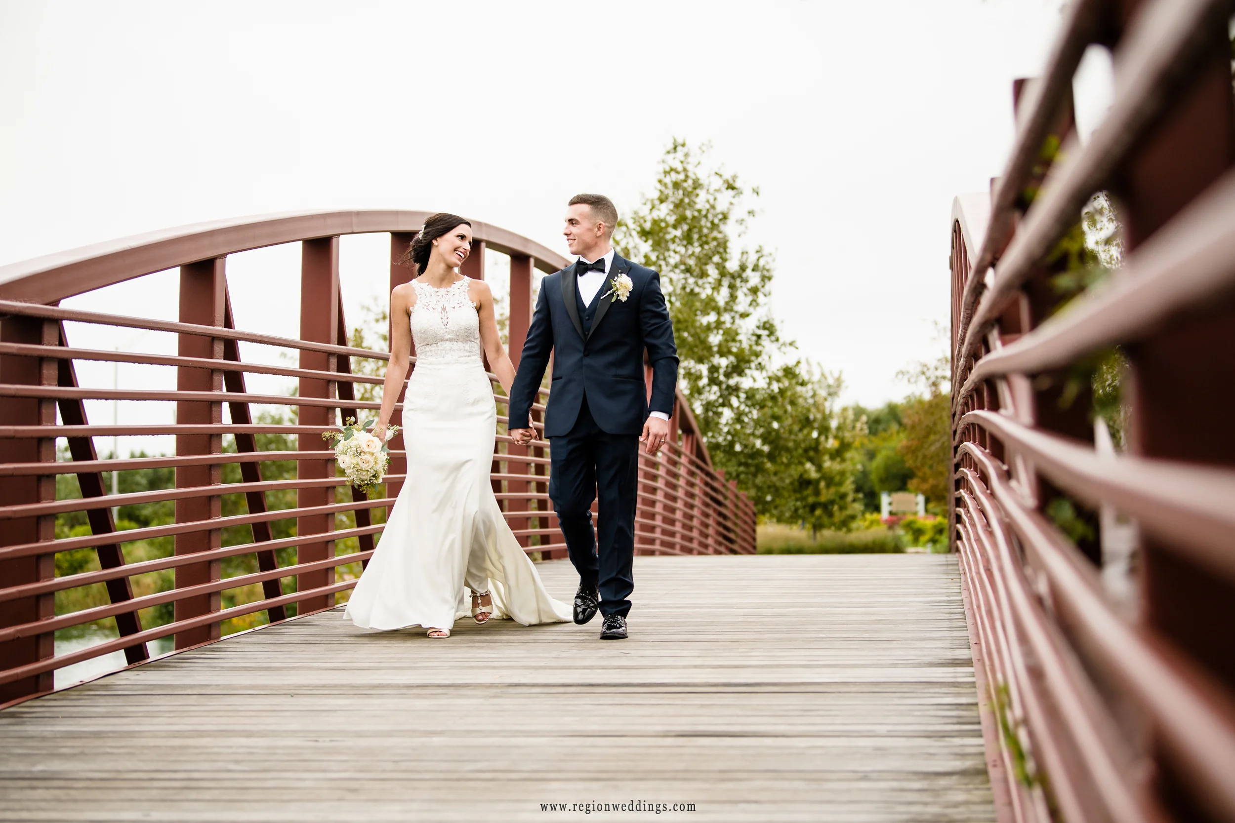 Bride and groom take a romantic walk on the bridge at Centennial Park.