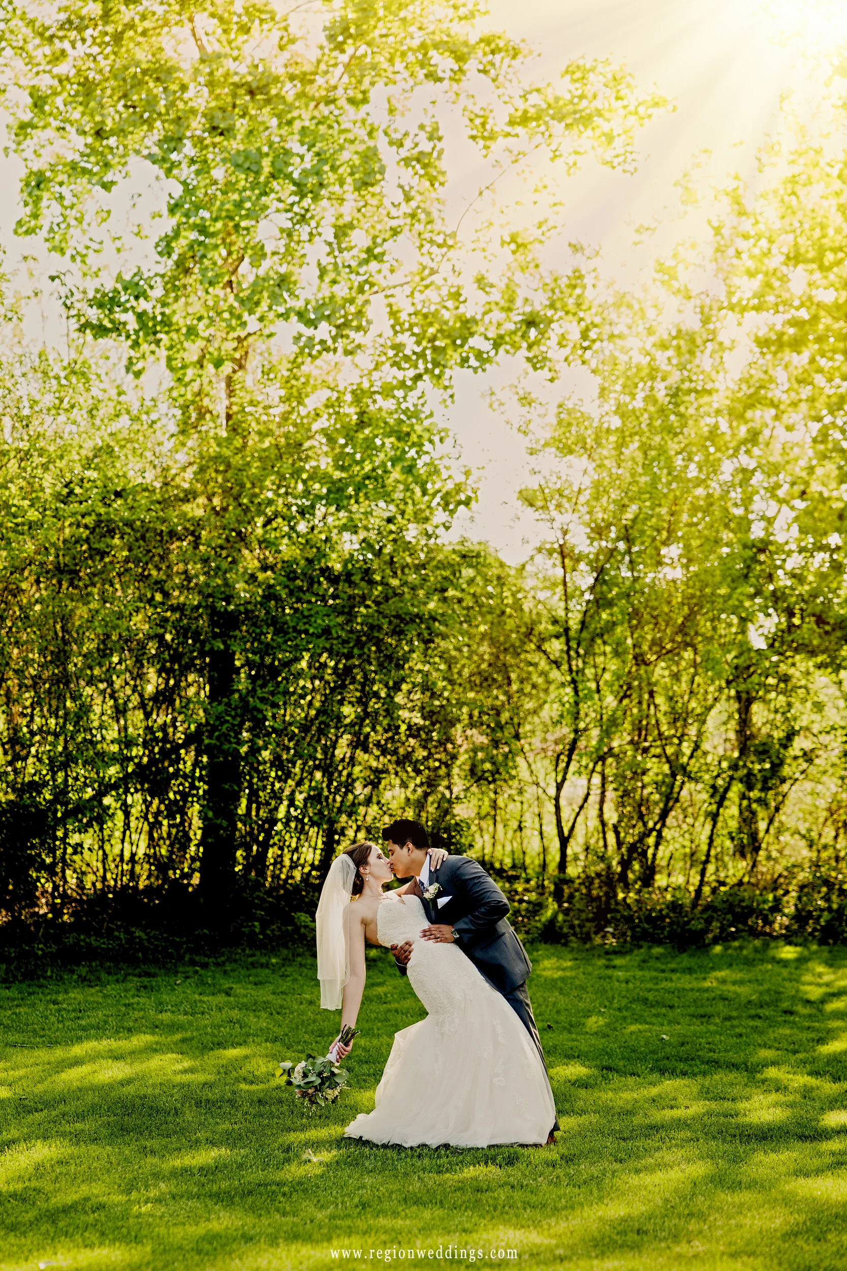 Sun shines upon the bride and groom during a romantic dip.