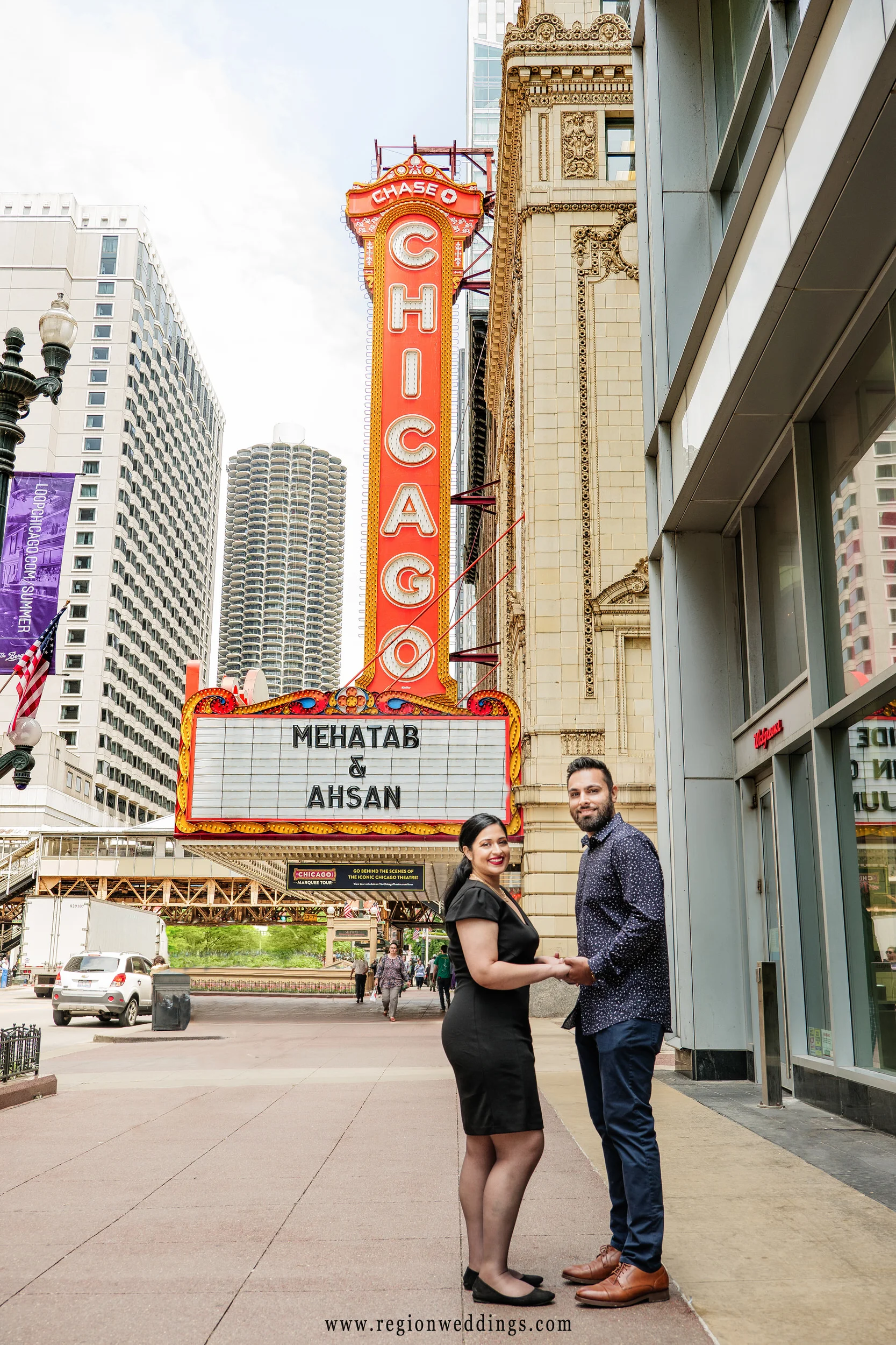A couple poses in front of the Chicago Theater for their engagement photo session.