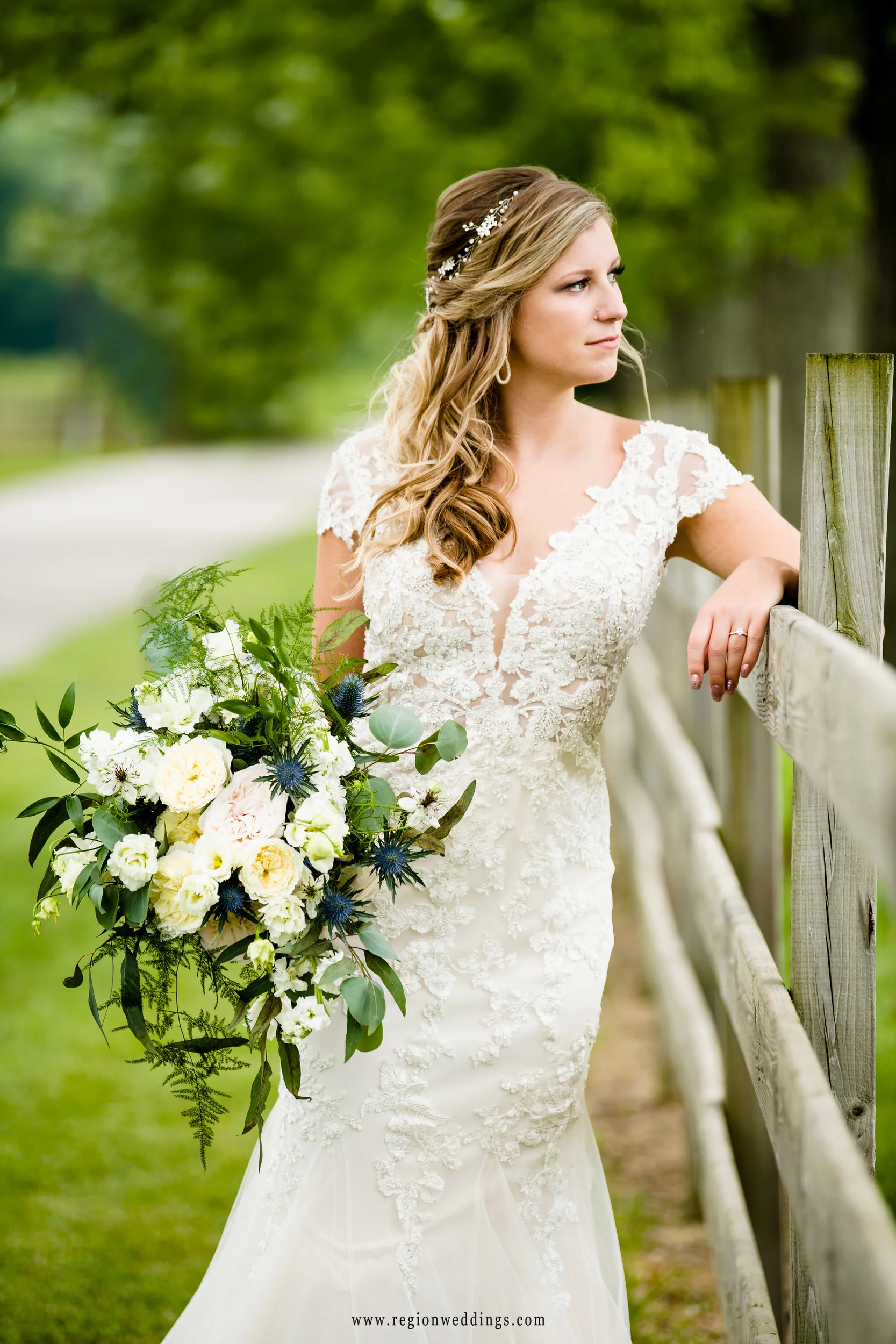 The bride leans against a rustic fence on the grounds at County Line Orchard.