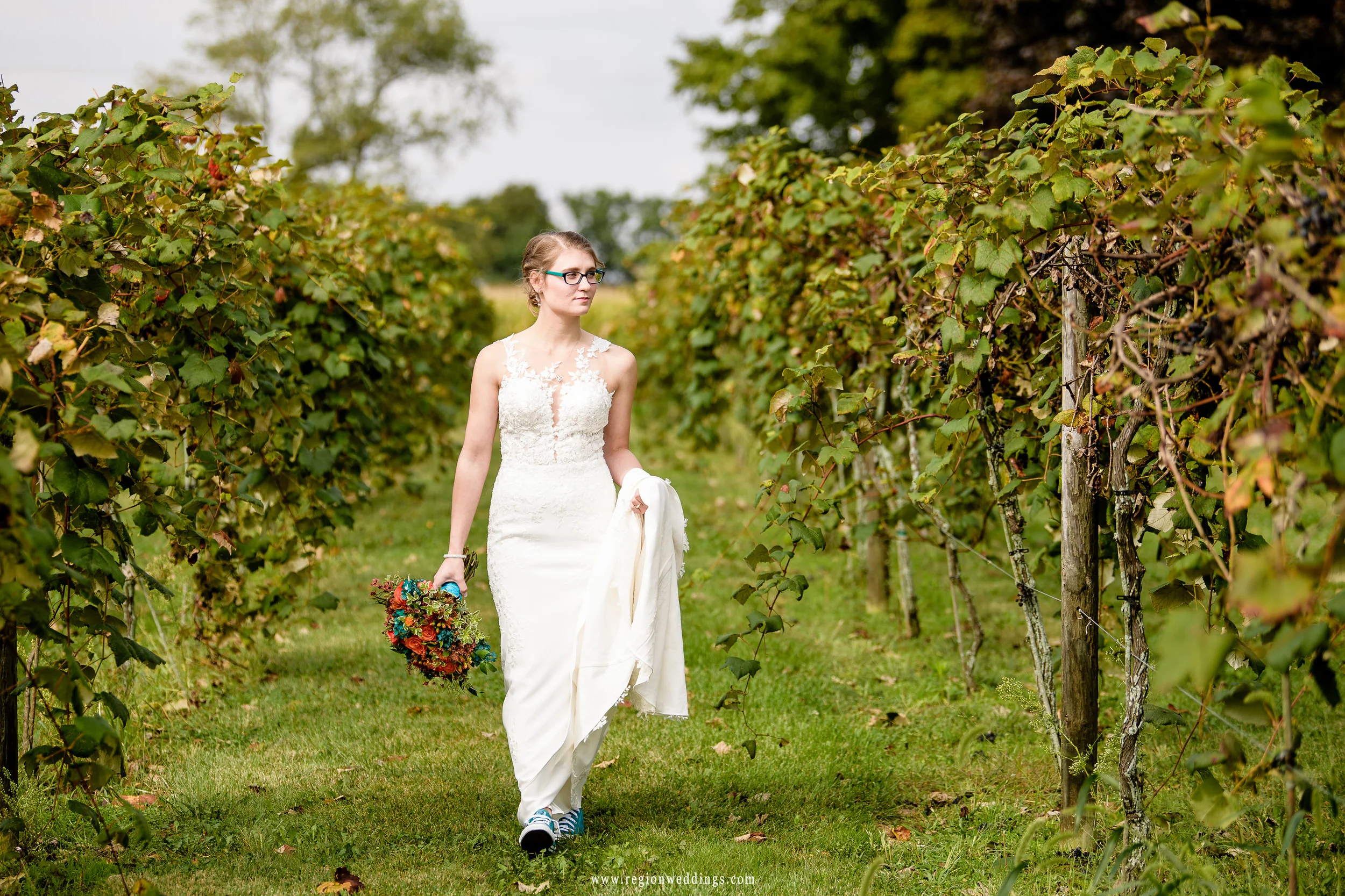A boho styled bride walks along the grape orchards in her Converse All Star sneakers.