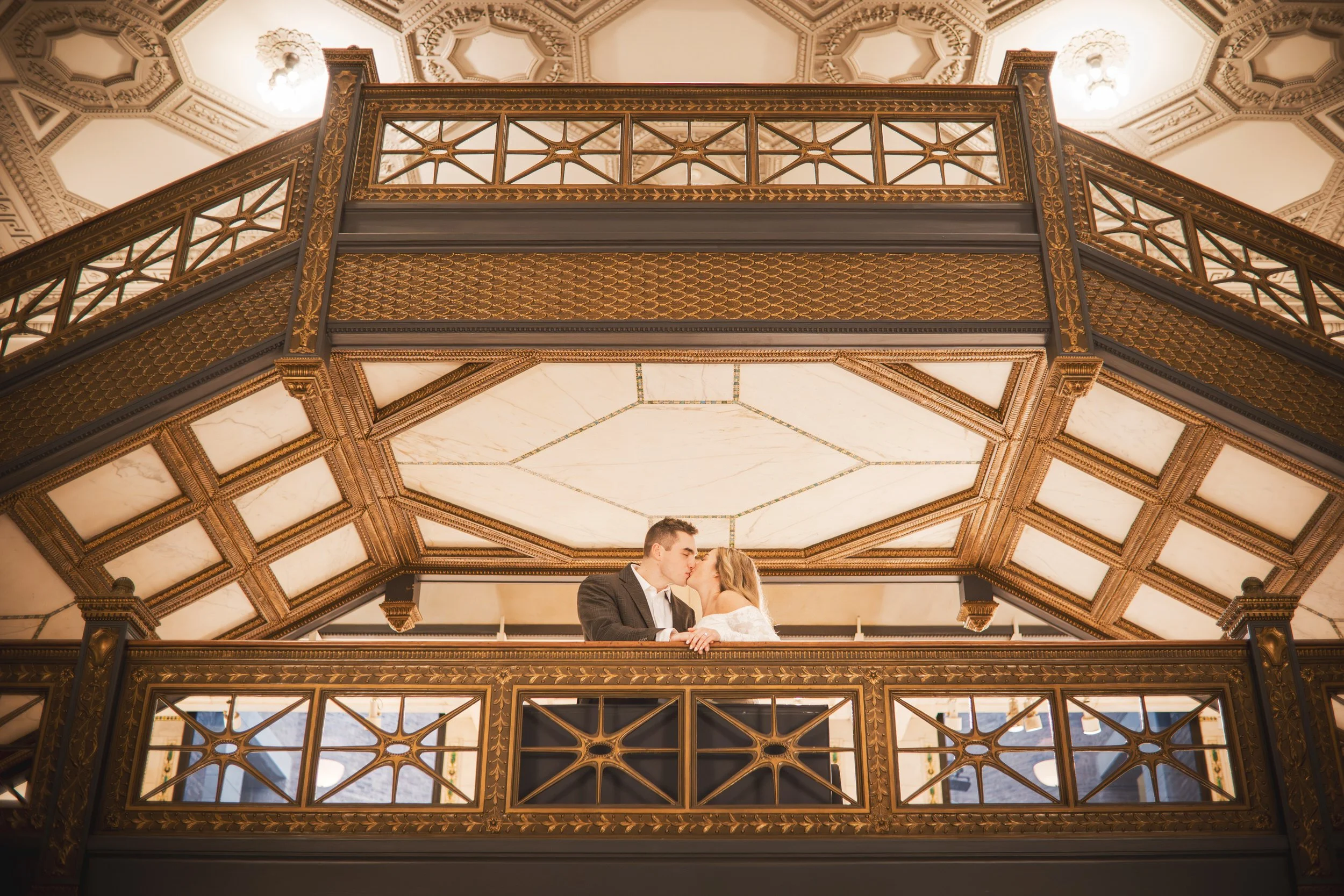 A couple kisses on a balcony at the Chicago Cultural Center.