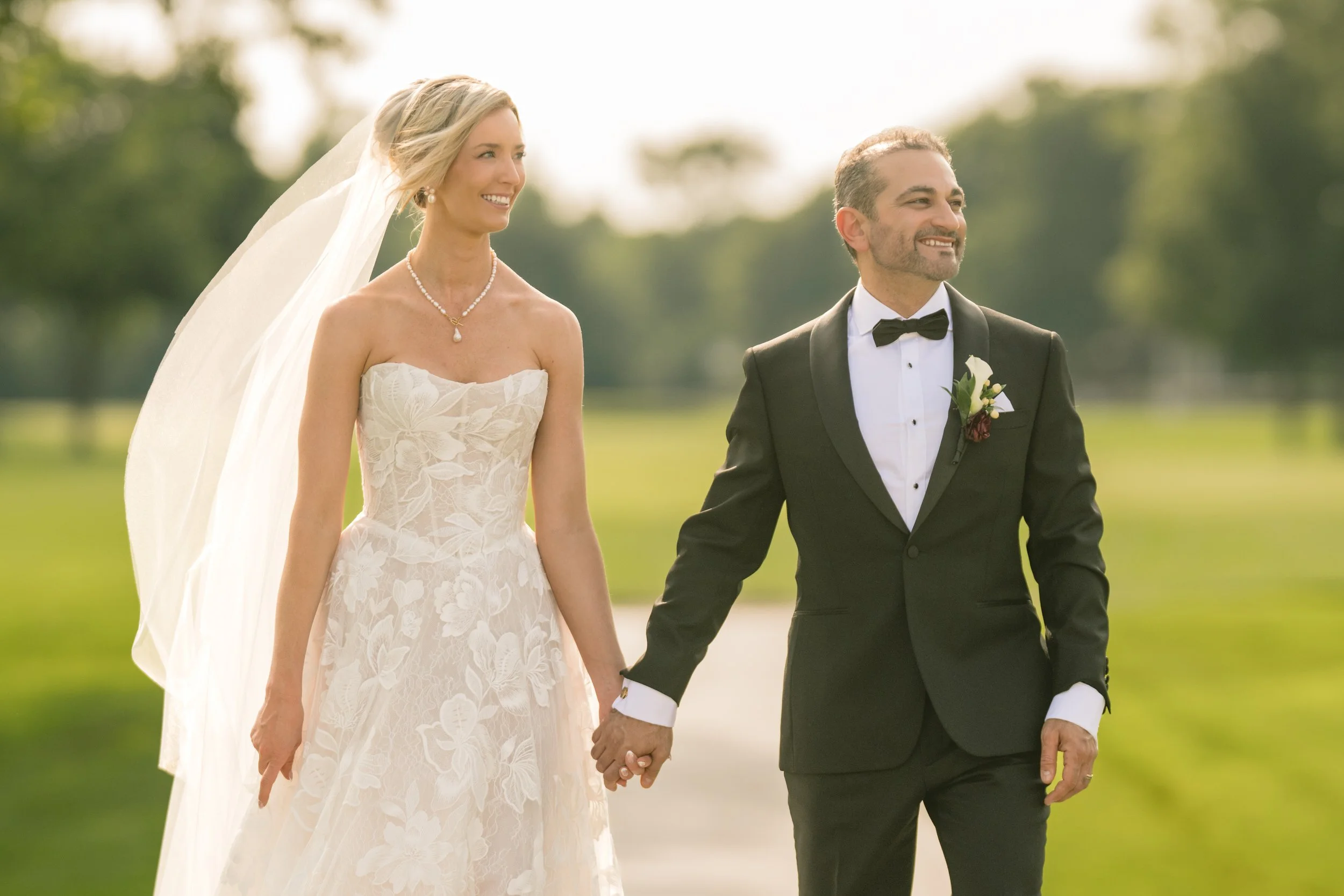 The bride and groom smile and look toward their wedding guests in a candid wedding photos.