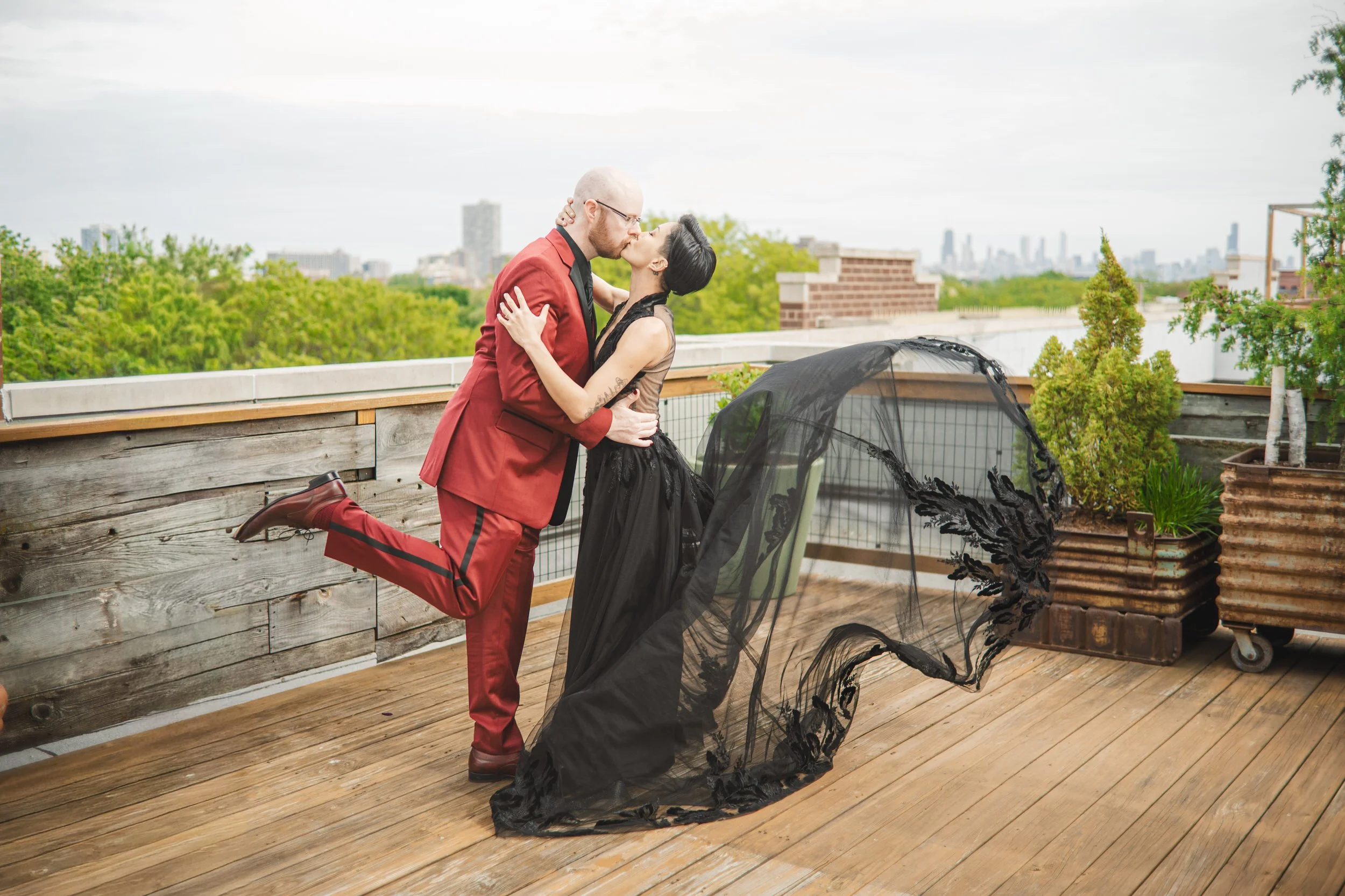 The bride's train flies in the wind as she receives a kiss from the groom on a Chicago rooftop.