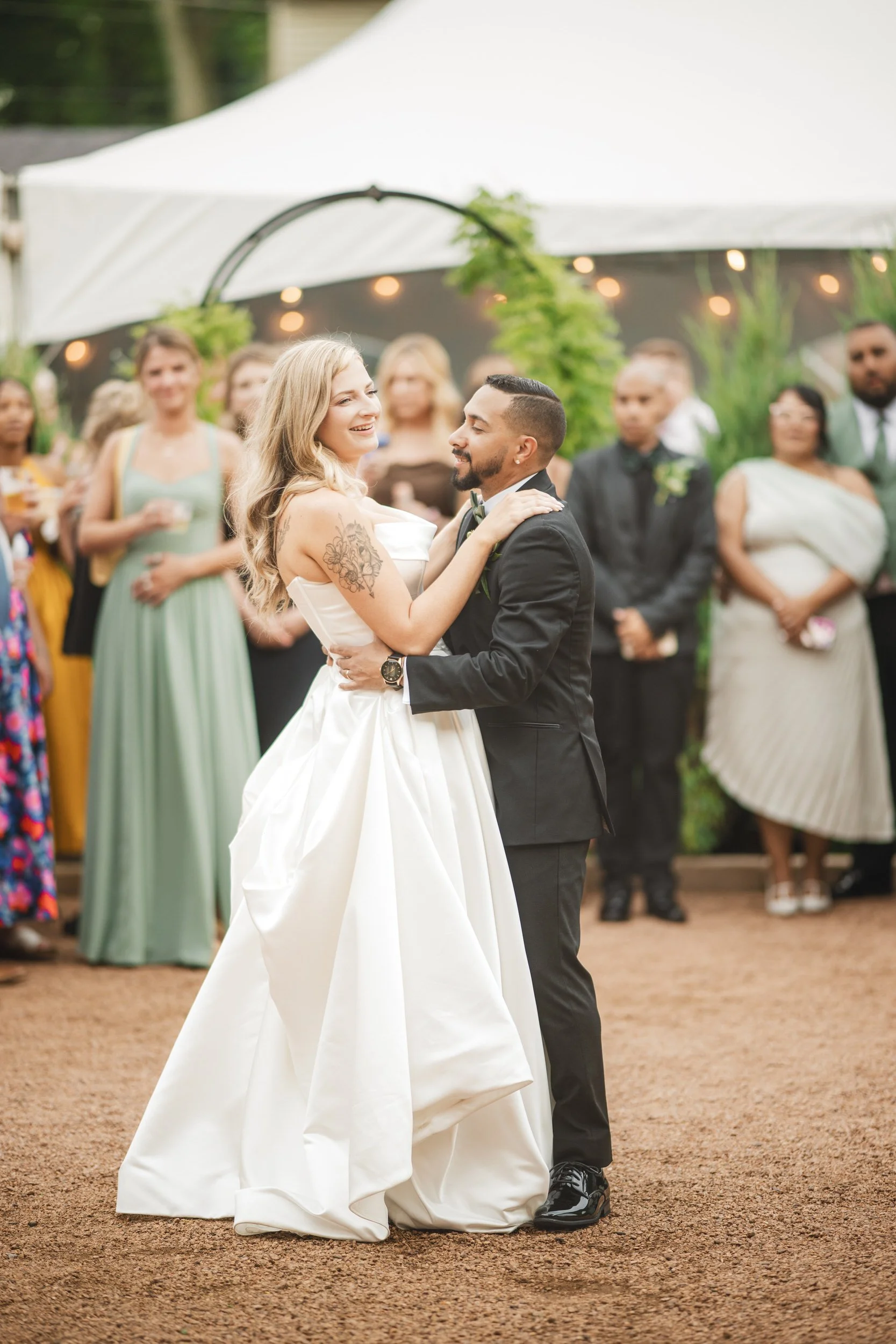 A bride and groom have their first dance at intimate wedding venue Jilly's Cafe, as guests circle around them.