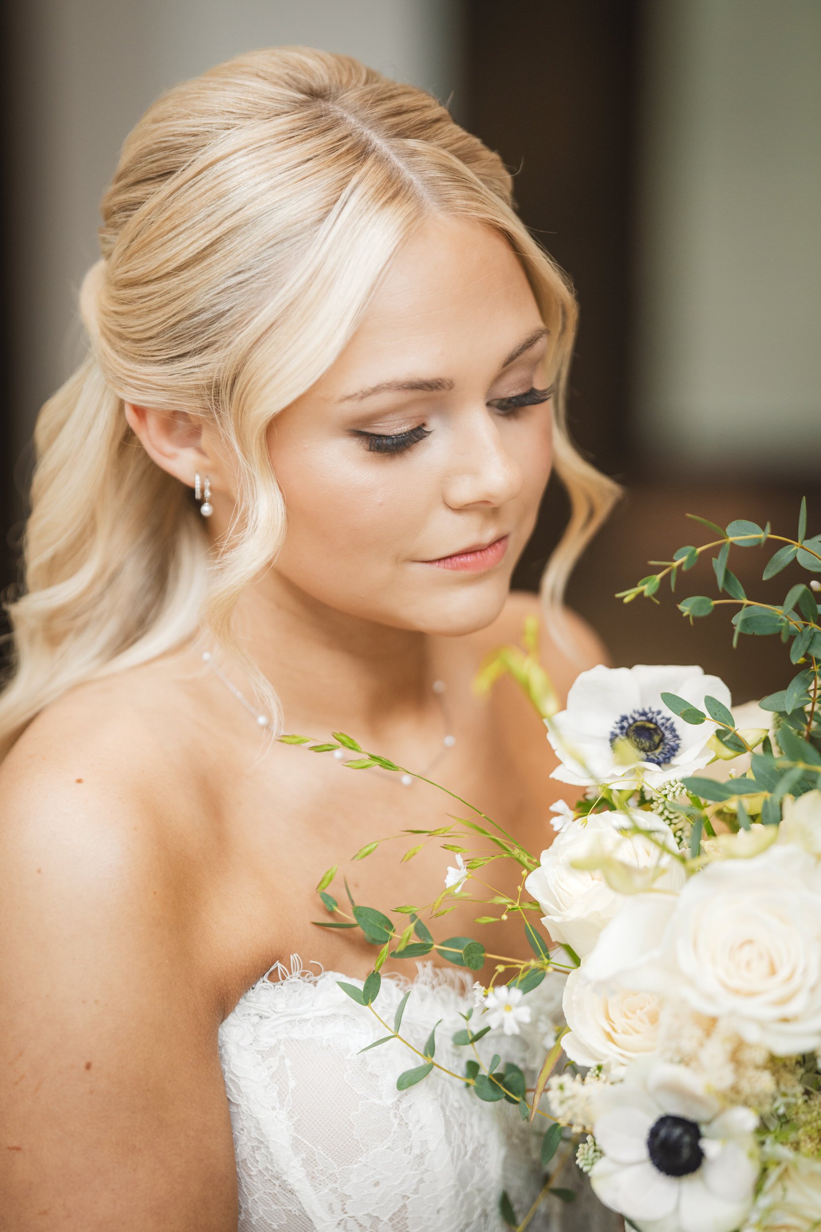 A bride looks down at her bouquet of flowers inside the bridal suite at The Pavilion at Sandy Pines.