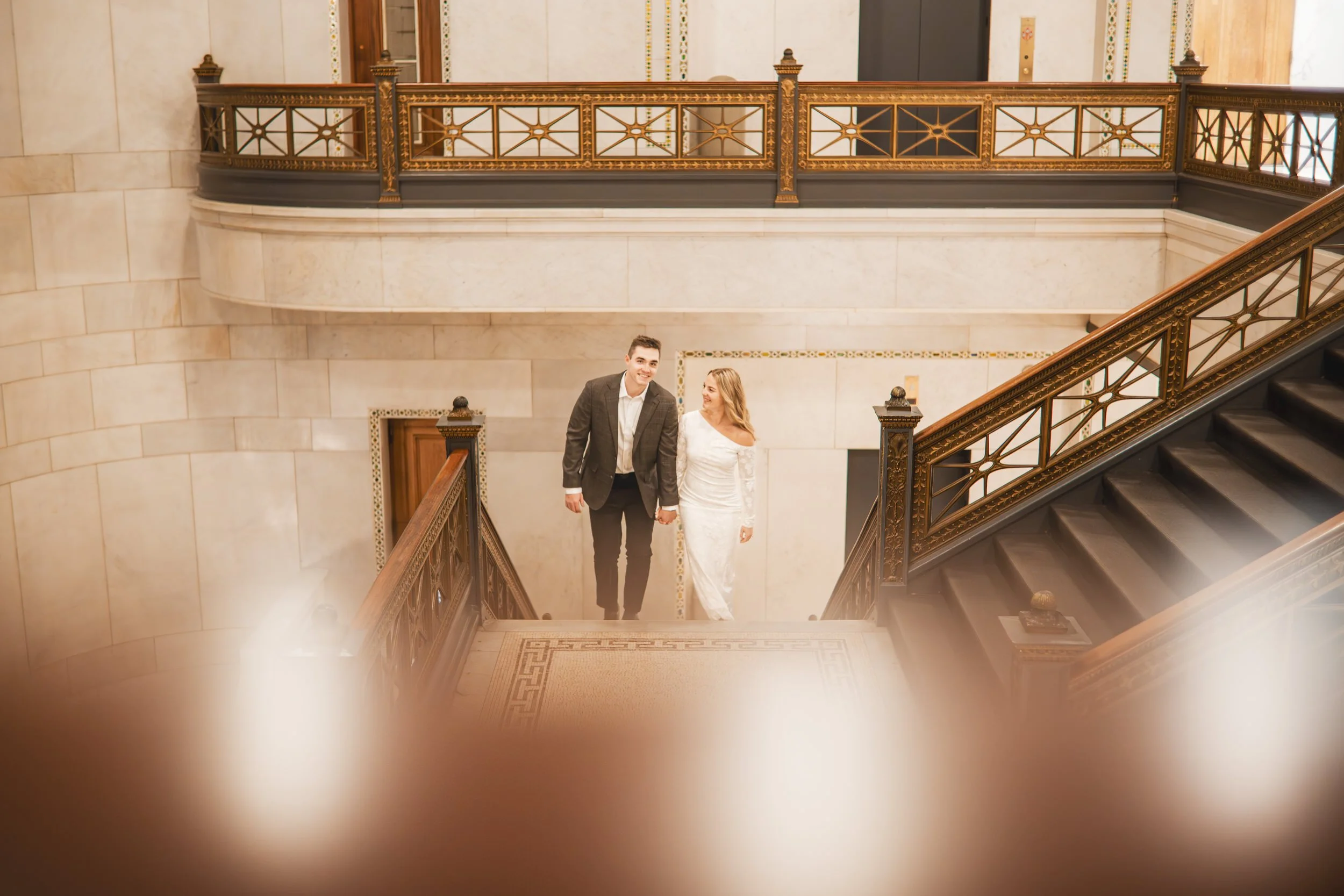 a young couple walks up the grand staircase of the Chicago Cultural Center during their Chicago engagement session.