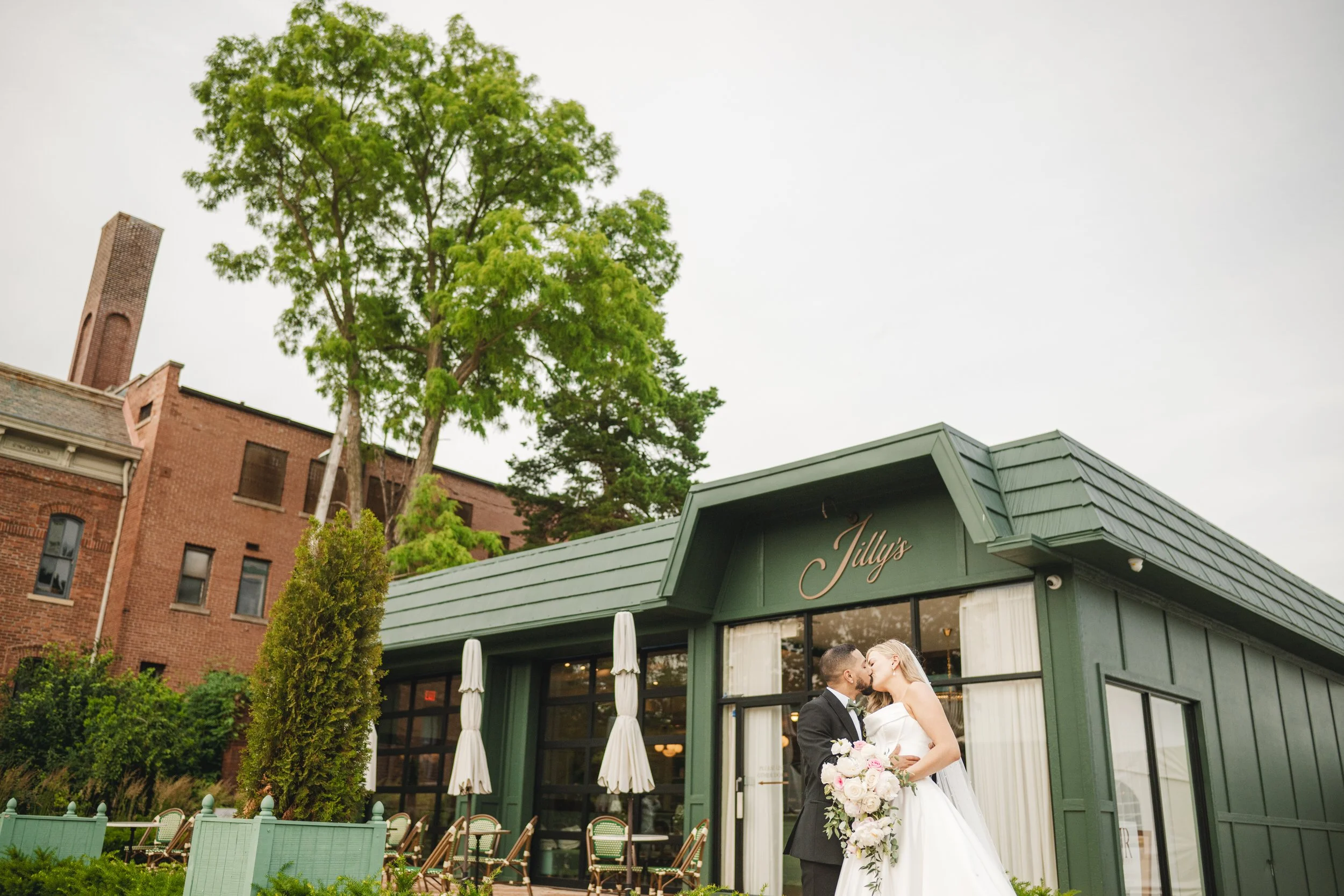 A bride and groom kiss beneath the sign at Jilly's Boutique Cafe in Crown Point, Indiana.