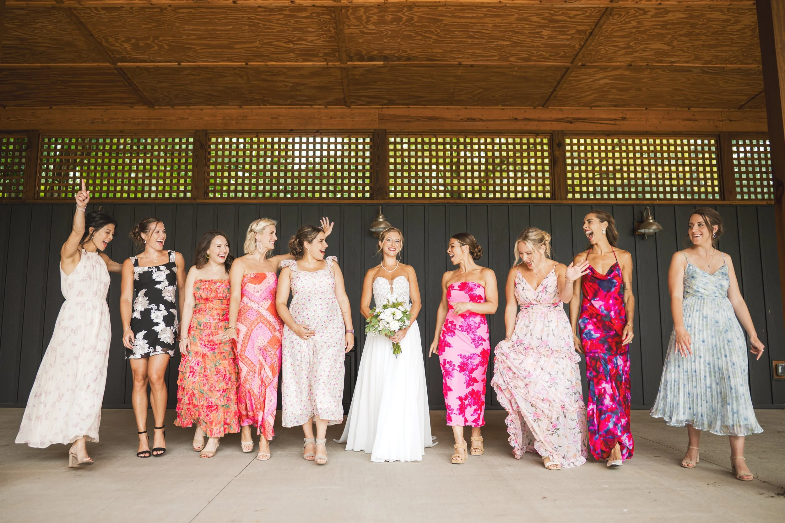 The bride and her bridesmaids take a spirited walk underneath an awning at White Oak Farm Venue.