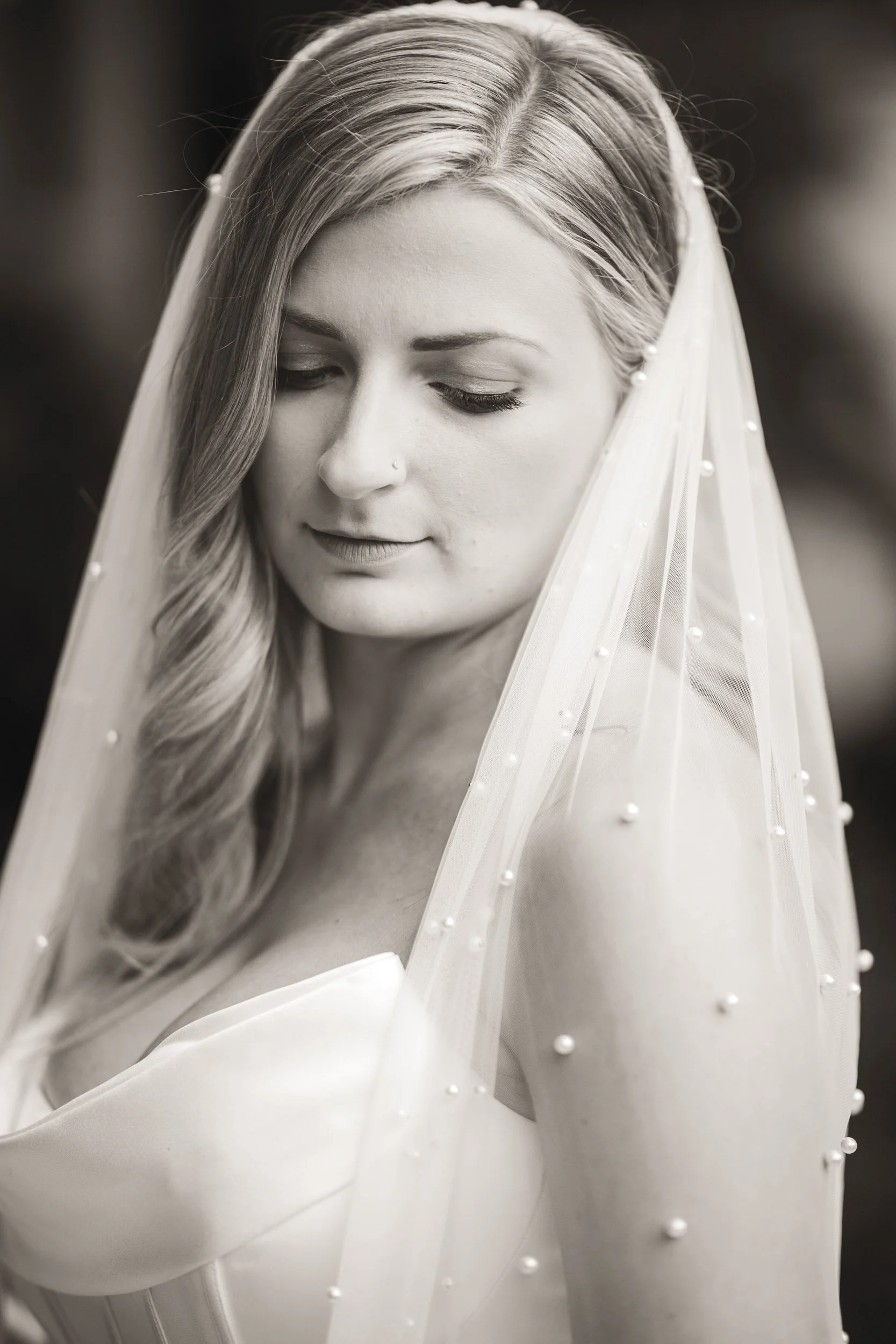 A bride with a studded veil over her shoulder in a black and white photo just before her ceremony.
