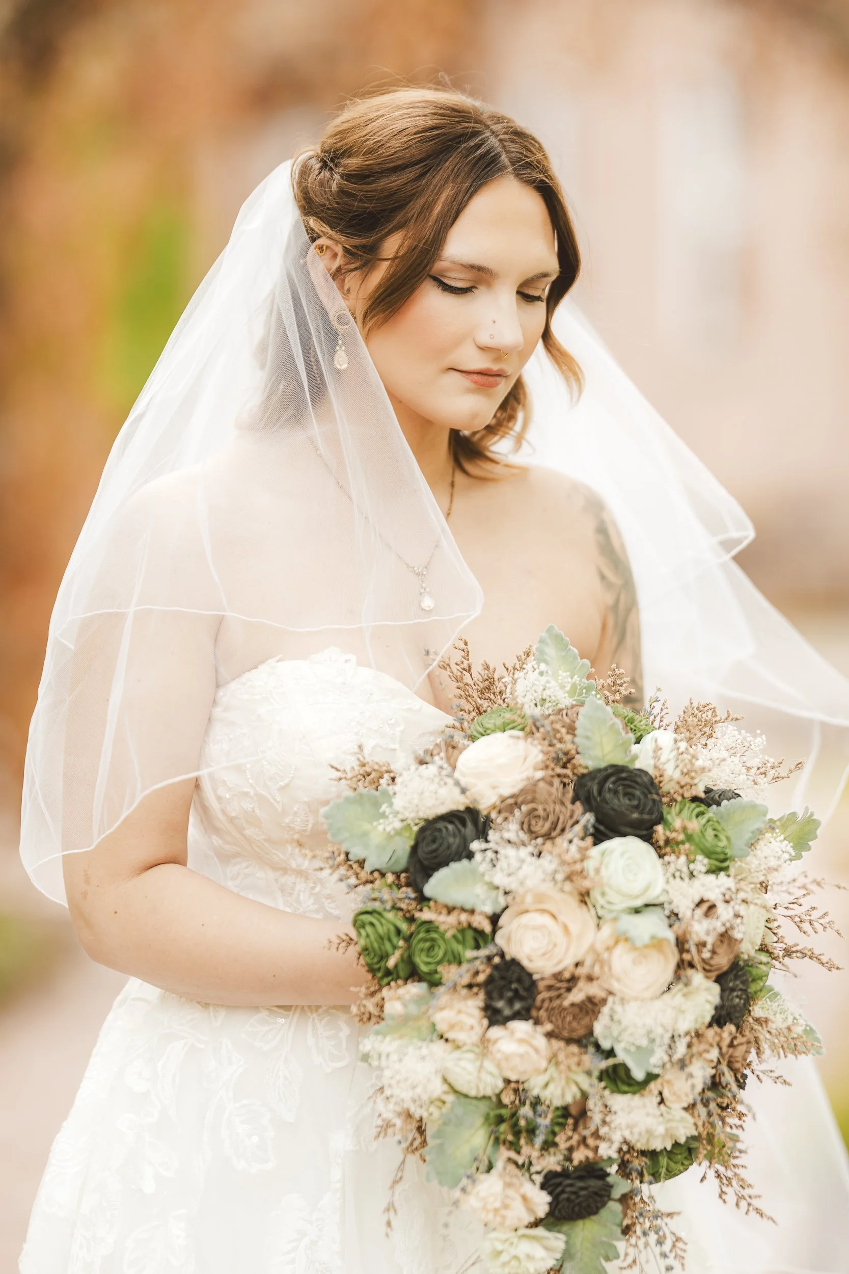 The bride looks down at her bouquet of wooden flowers.
