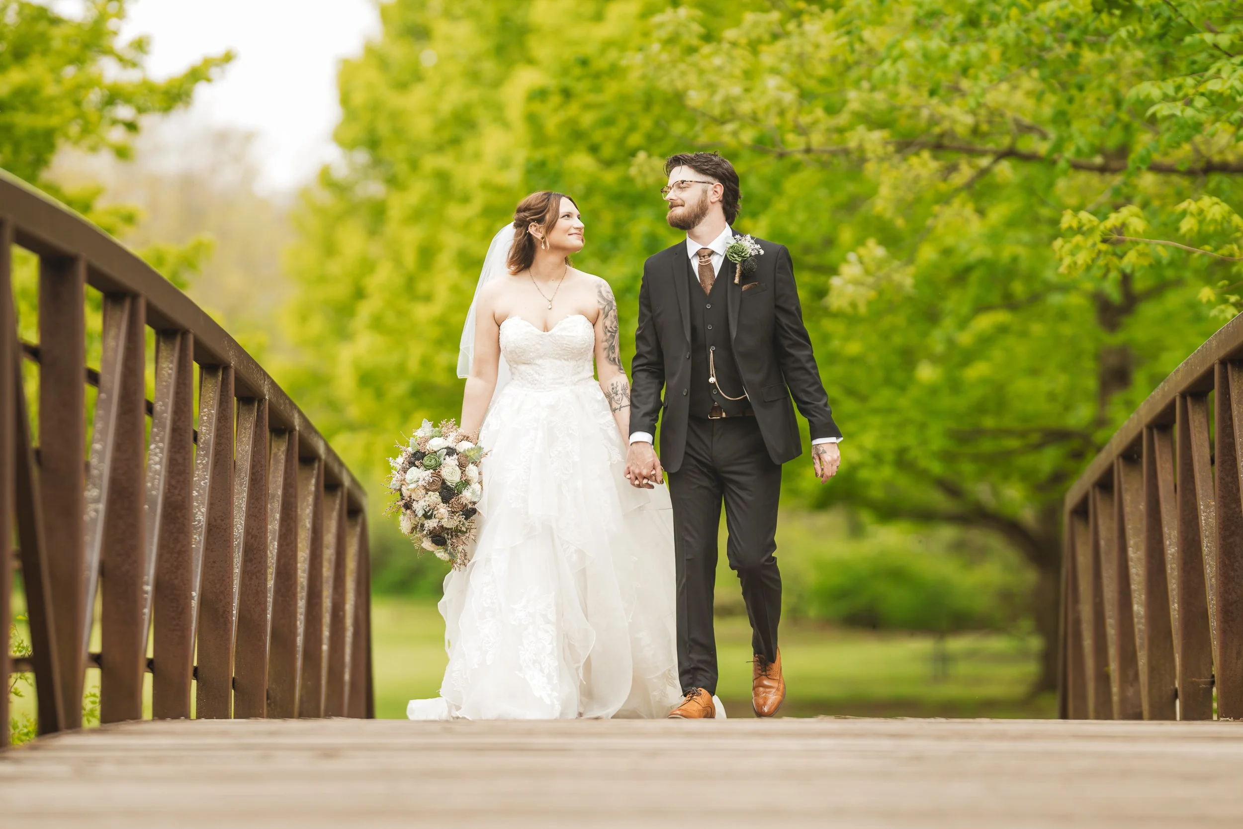 A newly married bride and groom walk across a bridge at Deep River County Park in Merrillville, Indiana.