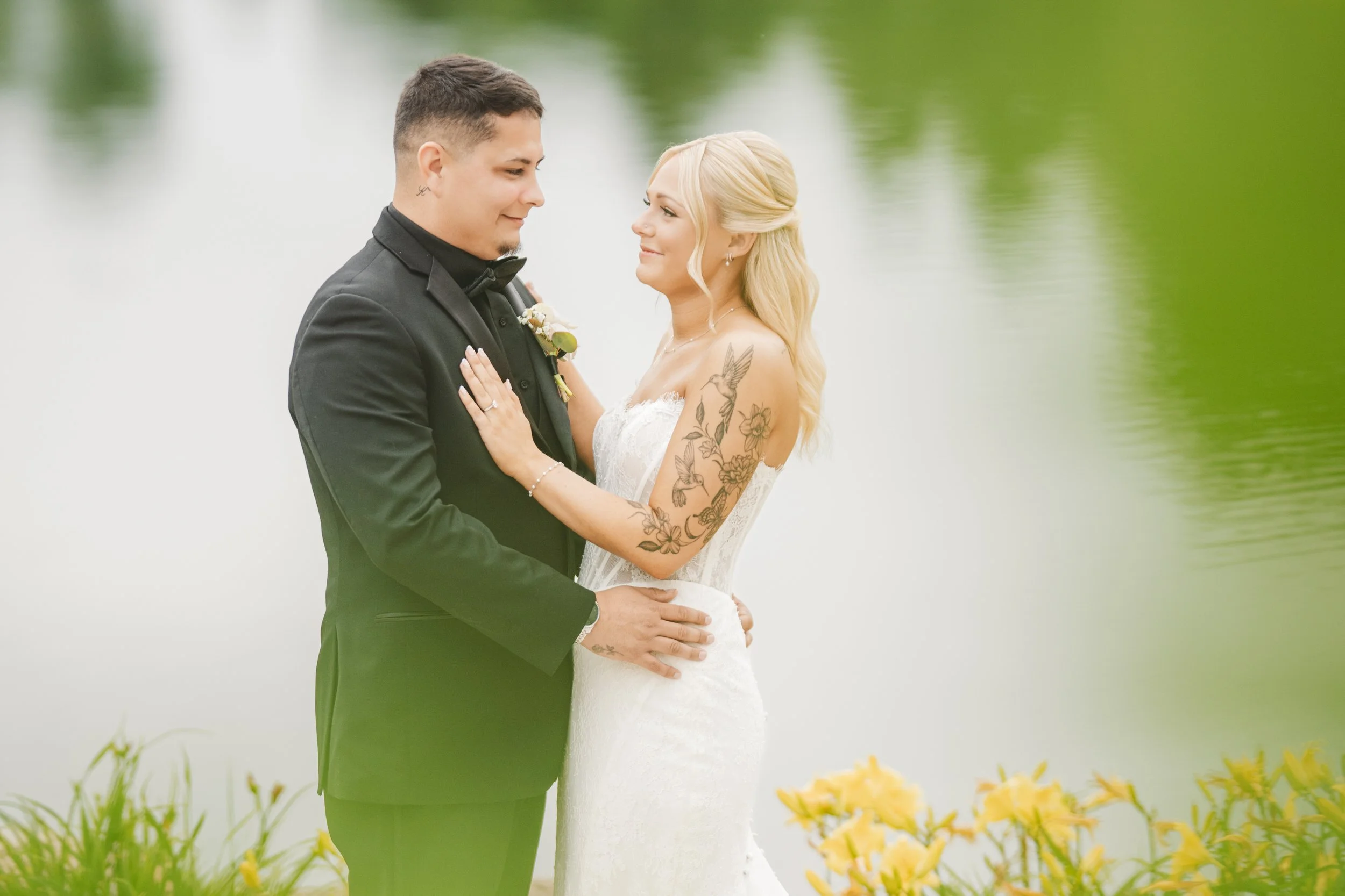 A bride and groom look into each other's eyes with reflective lake water in the background.